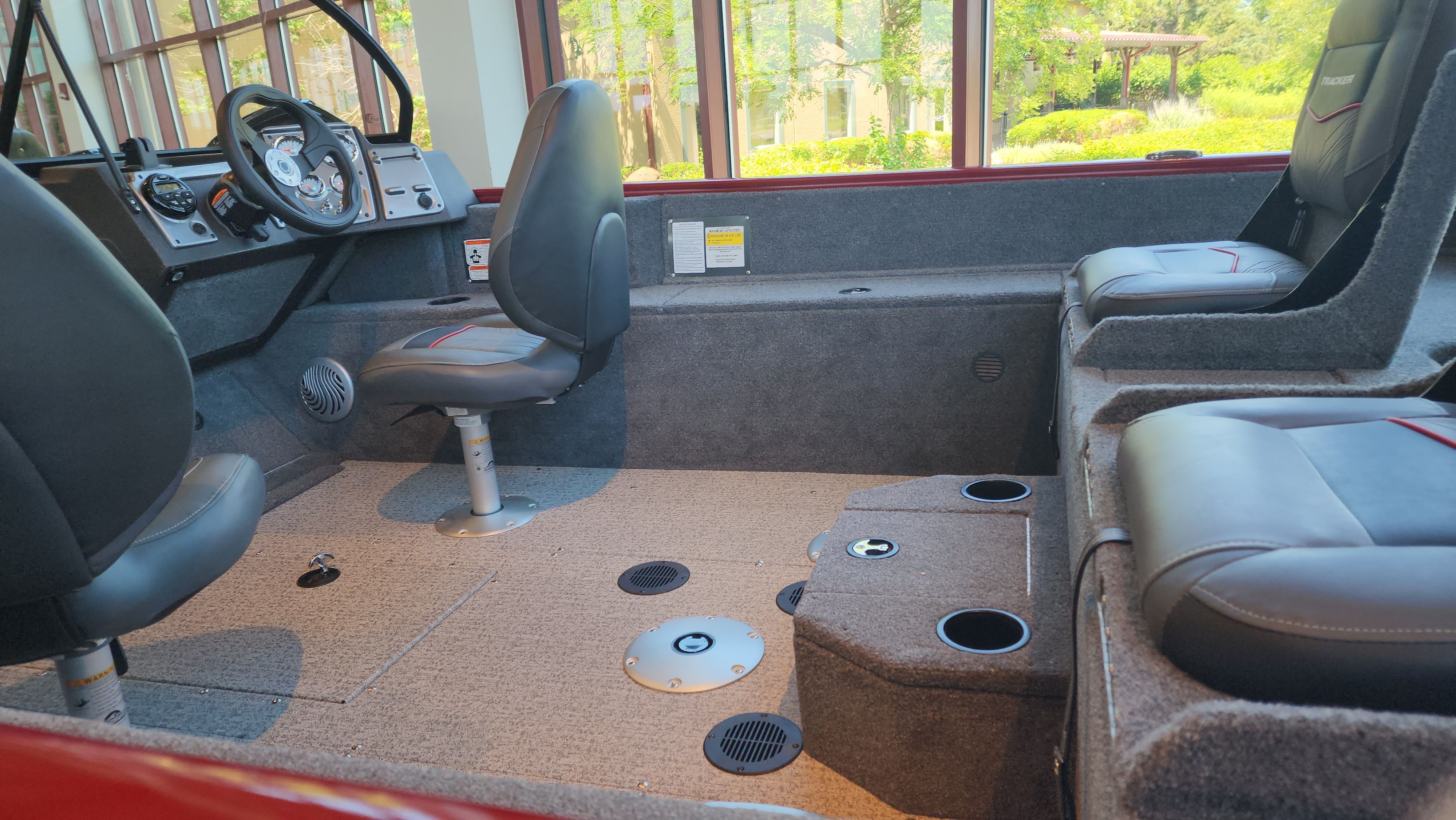 The image shows the interior of a 2023 Bass Tracker PGV175 with gray seats and carpeted flooring.