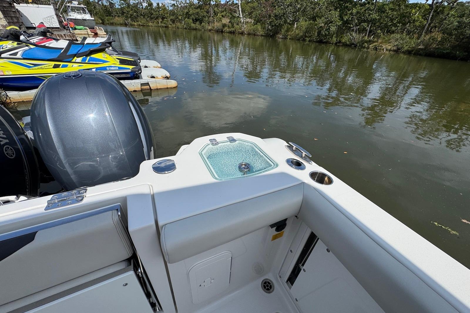 2022 Sailfish 276 DC boat with motor, docked near watercrafts on a calm river.