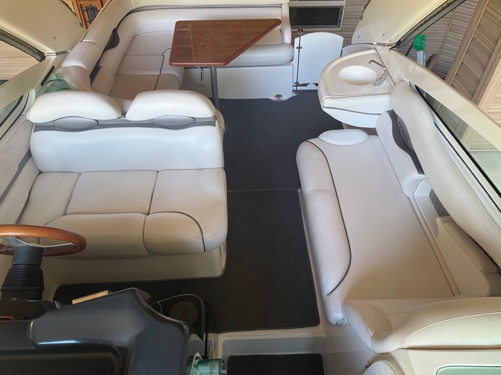 Interior of a 2007 Doral Monticello with white upholstered seating and a wooden table.