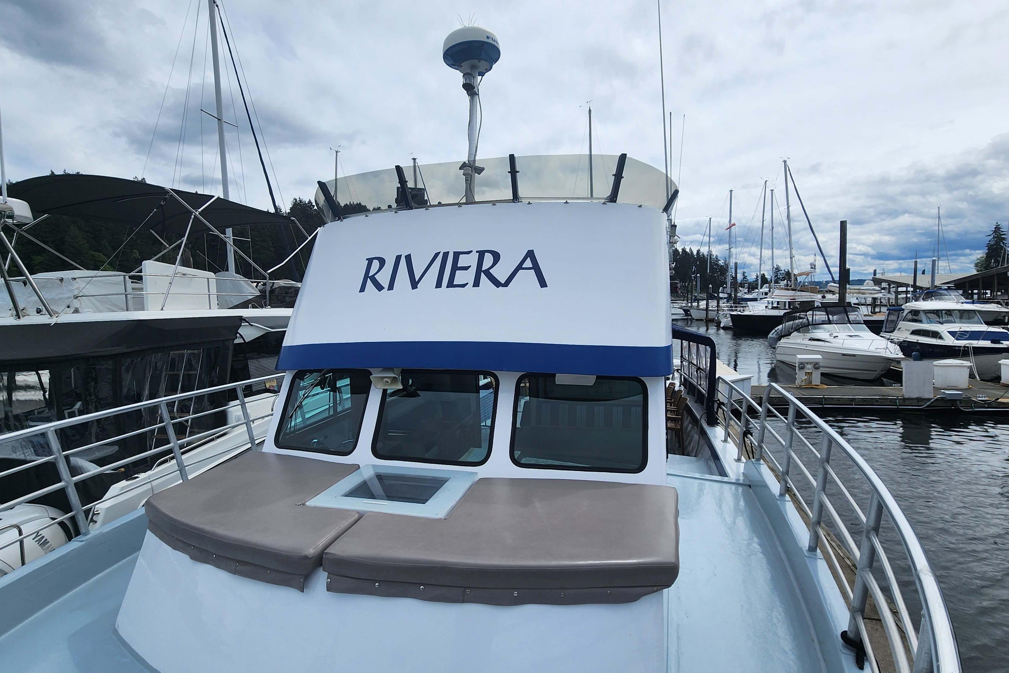 1964 Grandy Tour Boat "Riviera" docked at marina, surrounded by other boats.