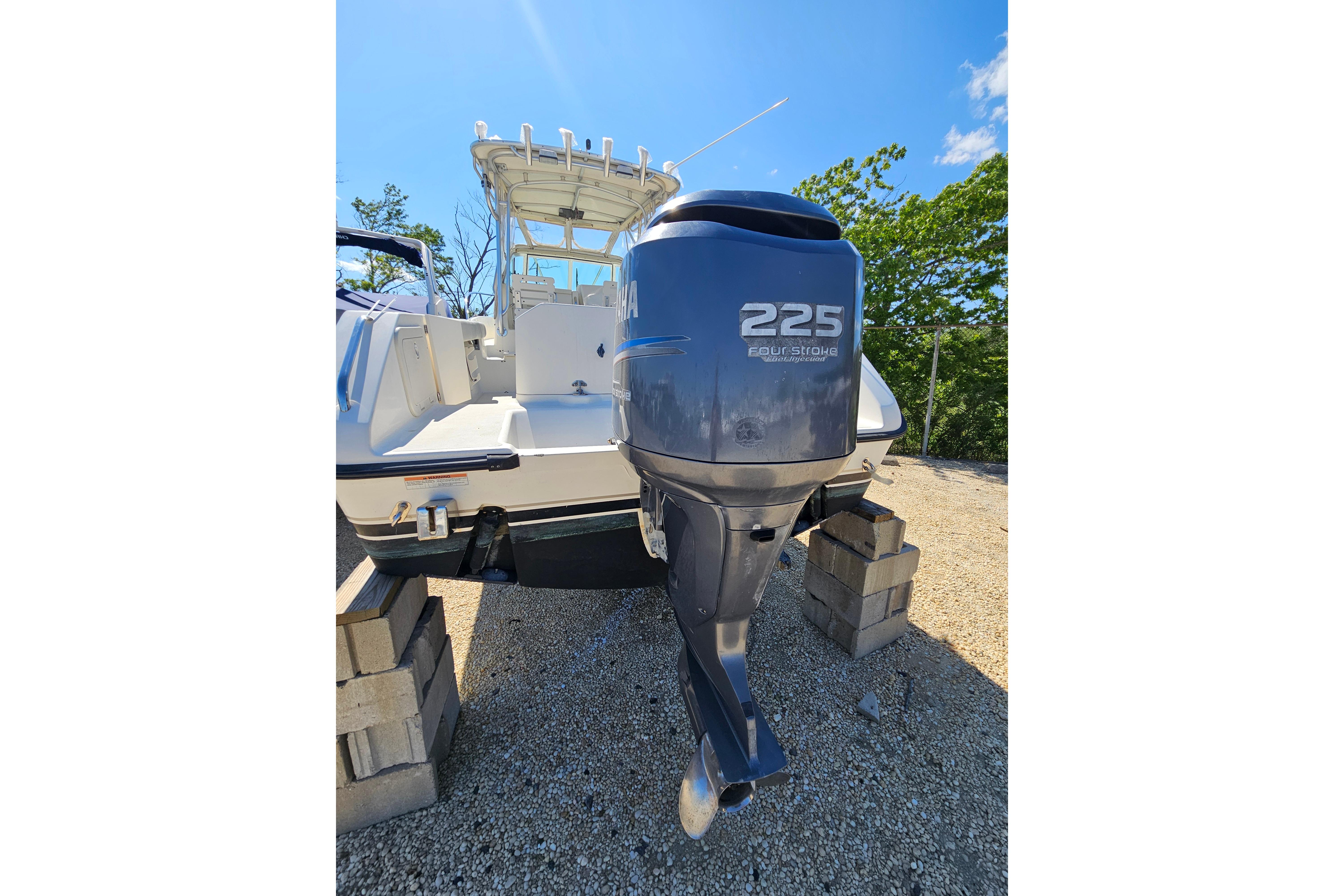 2004 Pursuit 2470 Walkaround boat with Yamaha 225 outboard motor on blocks.
