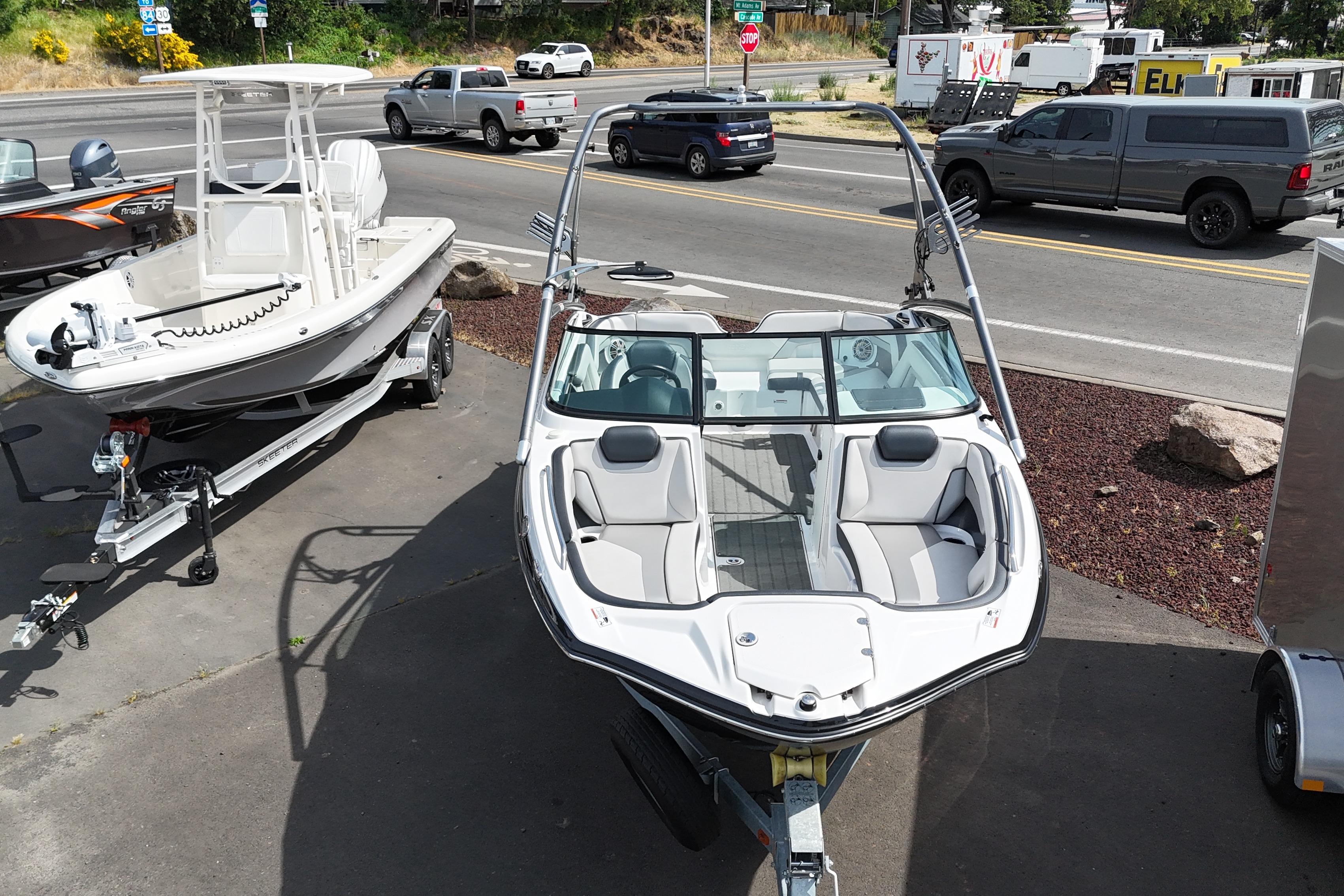 2016 Yamaha Boats 212X on trailer, parked beside another boat, with street view in background.