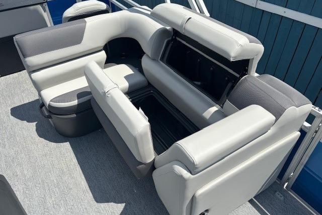 2026 Sun Tracker Fishin' Barge 20 DLX seating with storage compartments, gray upholstery.