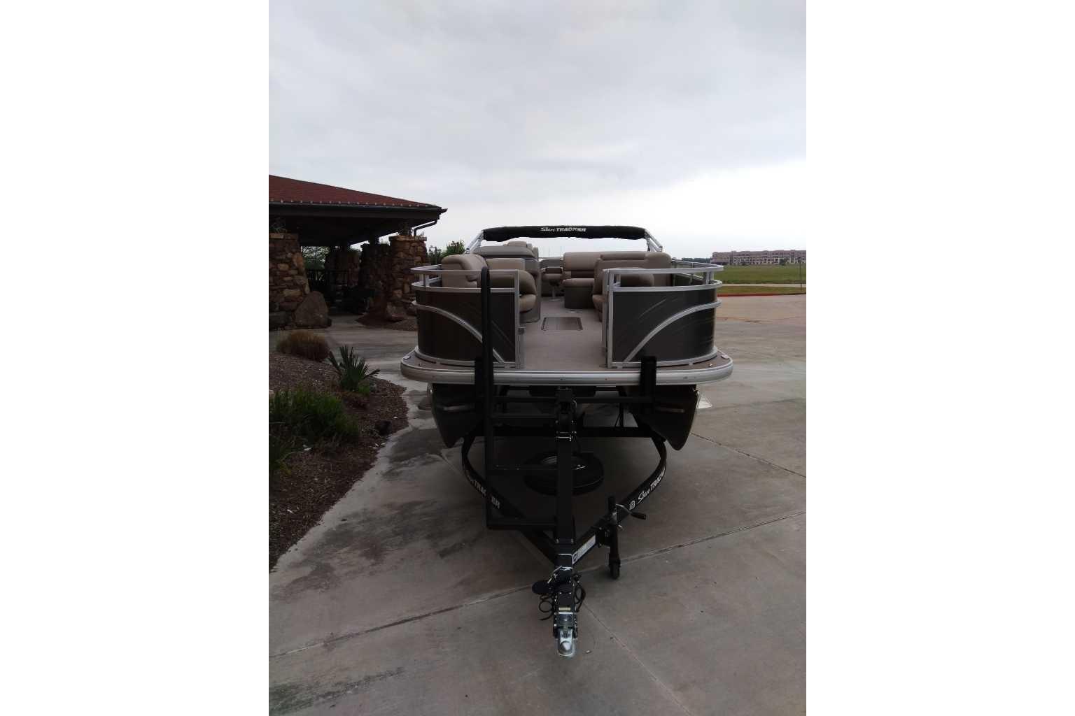 2025 Sun Tracker Fishin' Barge 22 XP3 pontoon boat on trailer, parked outdoors.