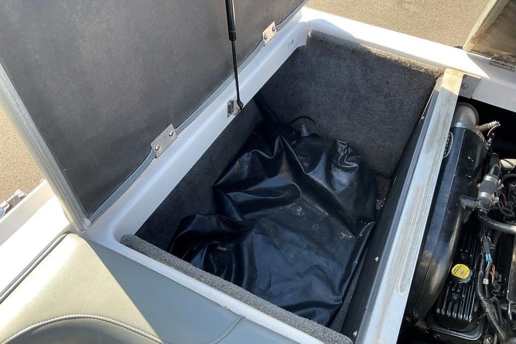 Open storage compartment in 2015 Moomba Outback V boat, showing engine and black cover.