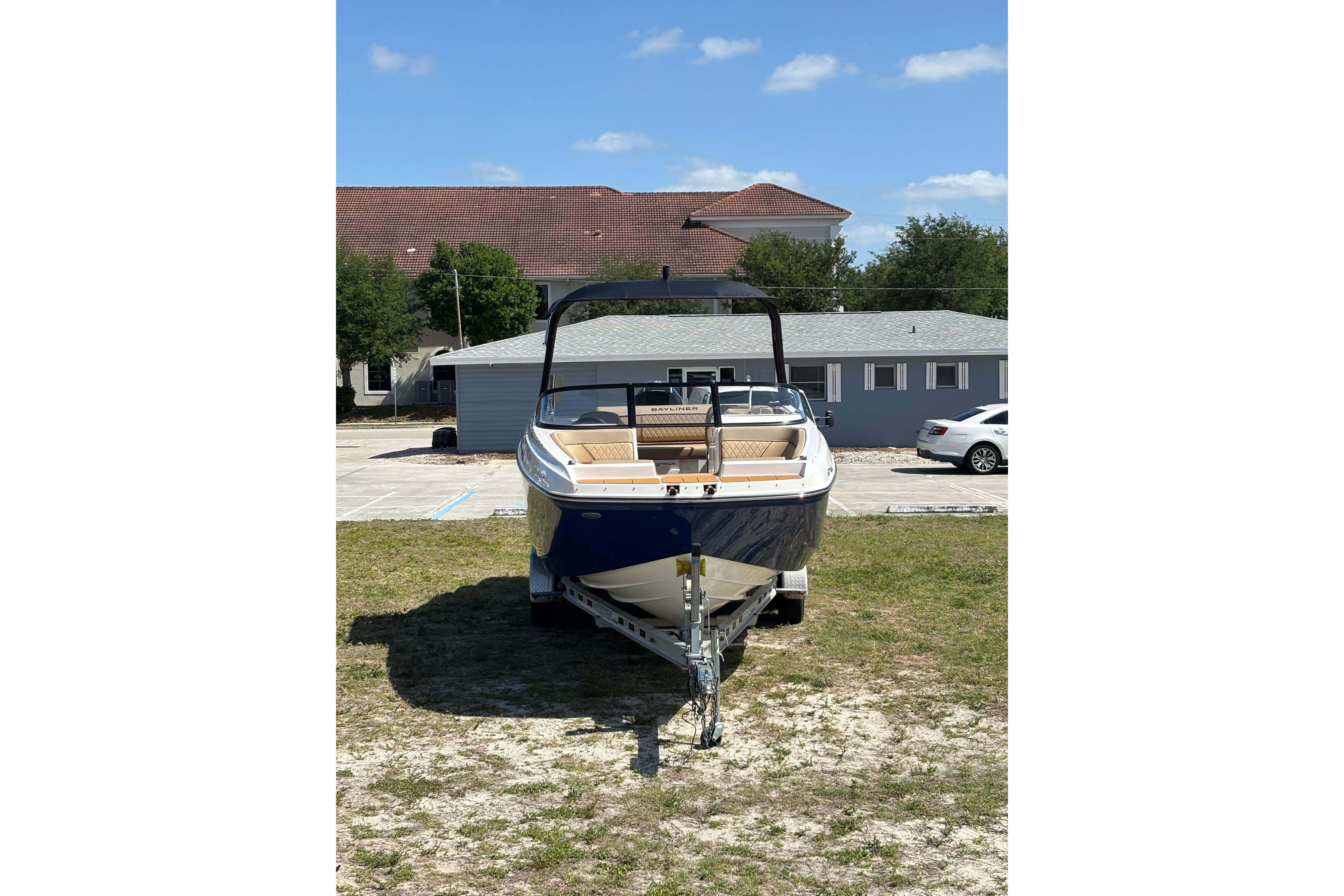2026 Bayliner D22 boat on trailer, parked outdoors under clear blue sky.