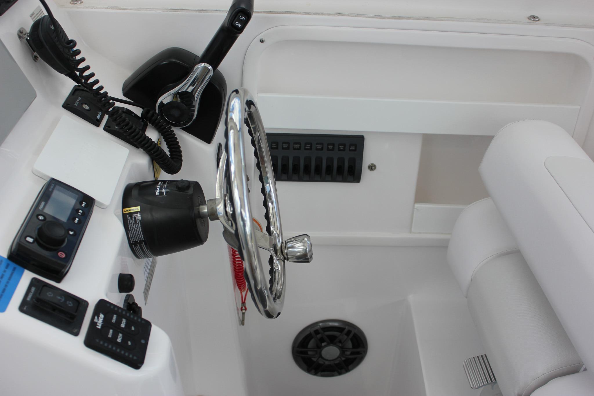 Interior helm of 2022 NorthCoast 235 Cabin boat with steering wheel and controls.