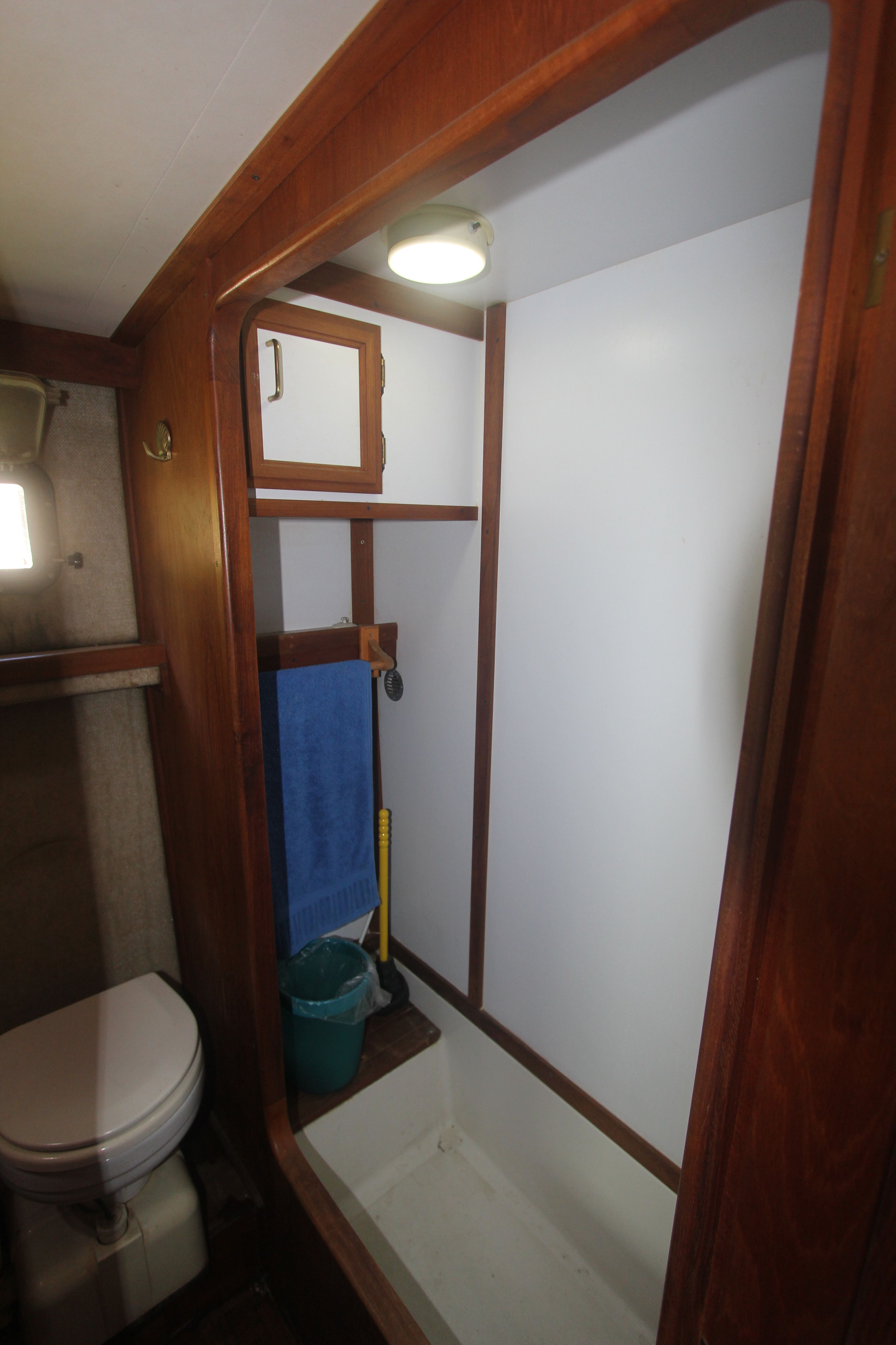 Interior view of a yacht cabin with toilet, shower, and wood paneling.