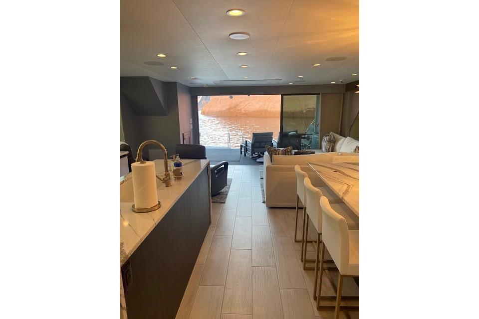 Luxurious interior of Adonia's 2021 "The Queen Elizabeth" yacht with modern furnishings and lake view.