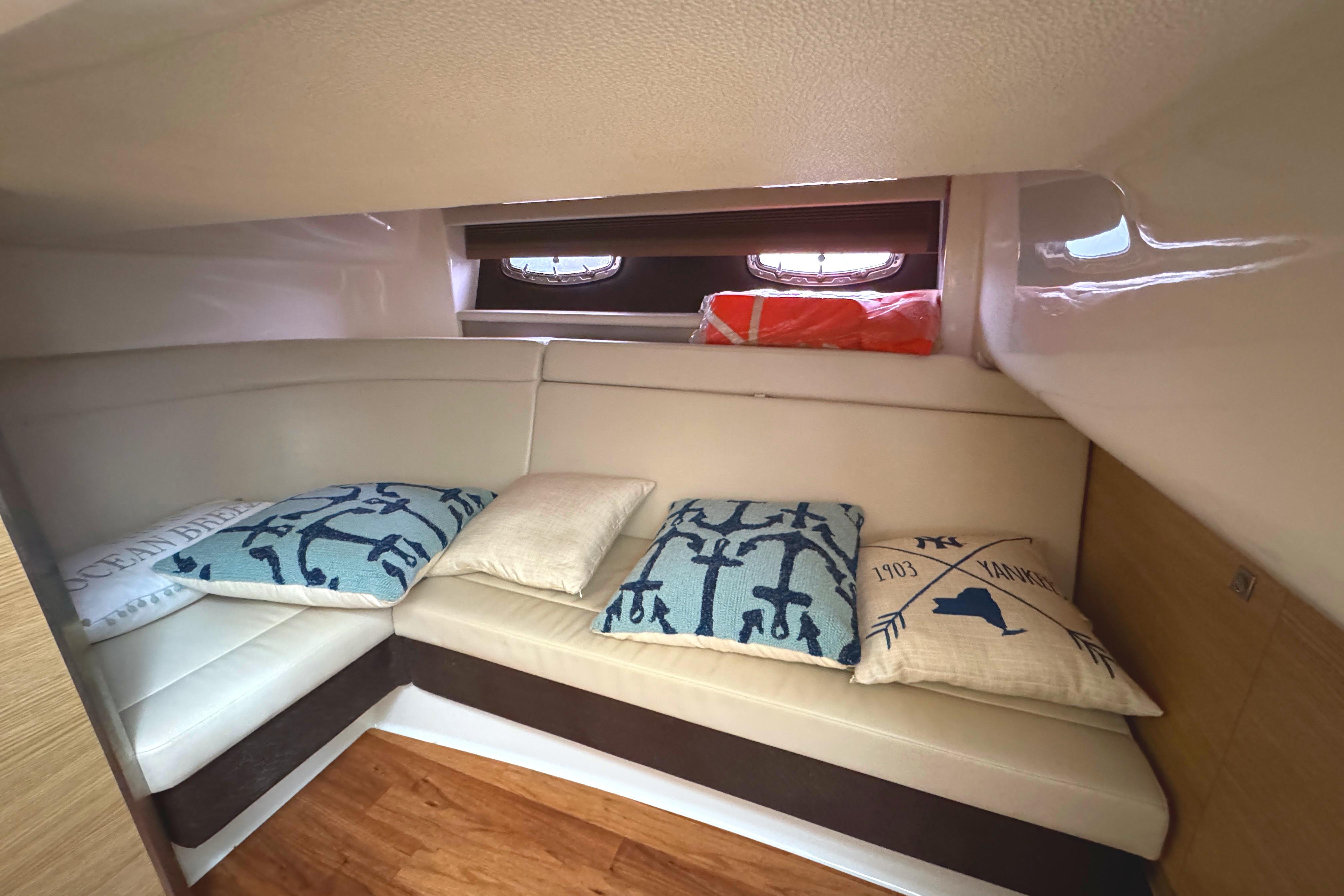 Cozy cabin interior of 2012 Chaparral 327 SSX with decorative pillows and wooden flooring.