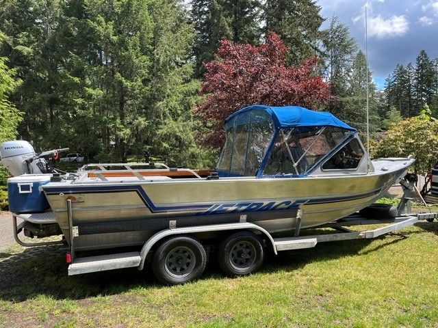 1986 Custom Jet Boat on trailer parked in forest setting.