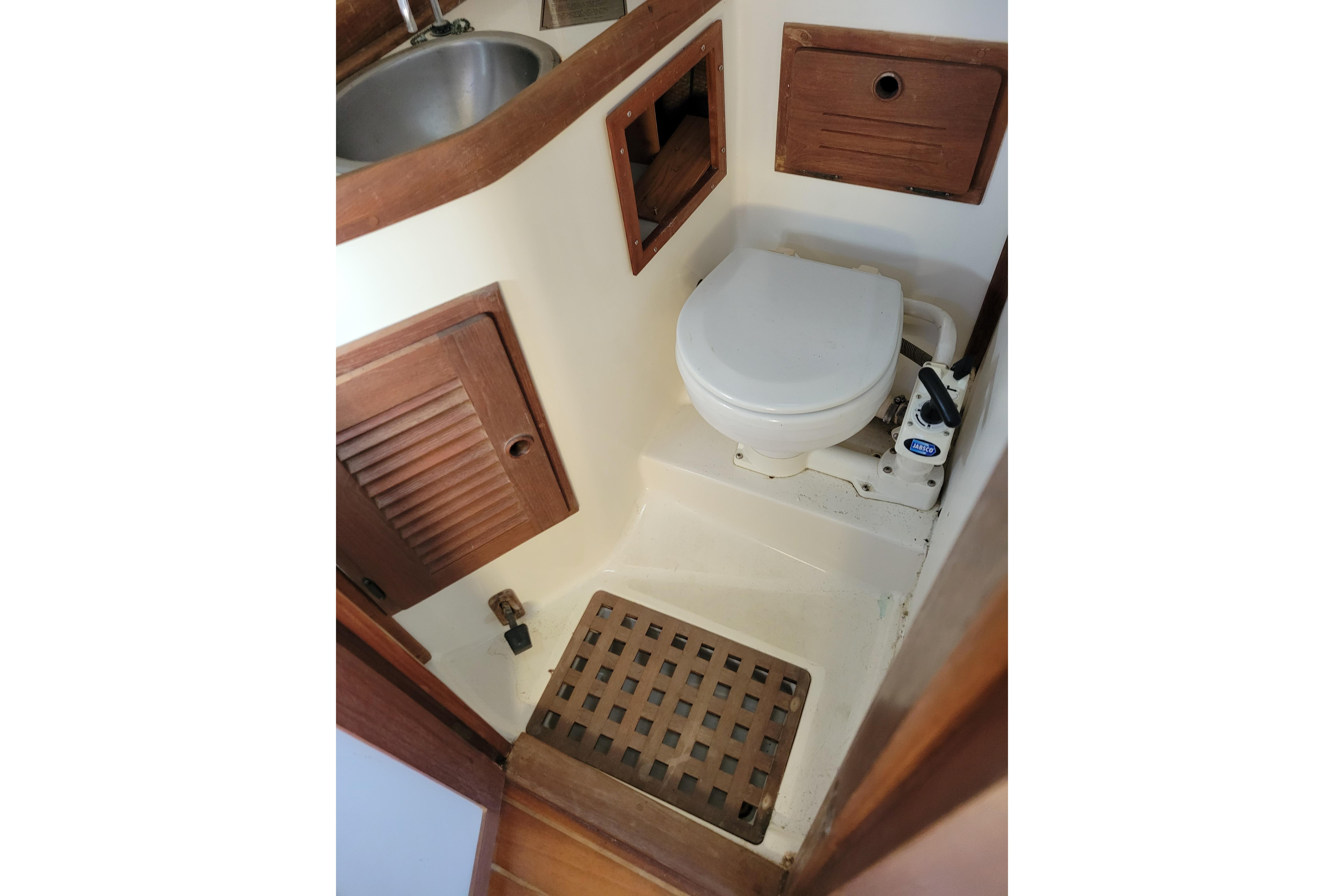 1981 Sea Sprite 34 sailboat bathroom with toilet, sink, and wooden accents.