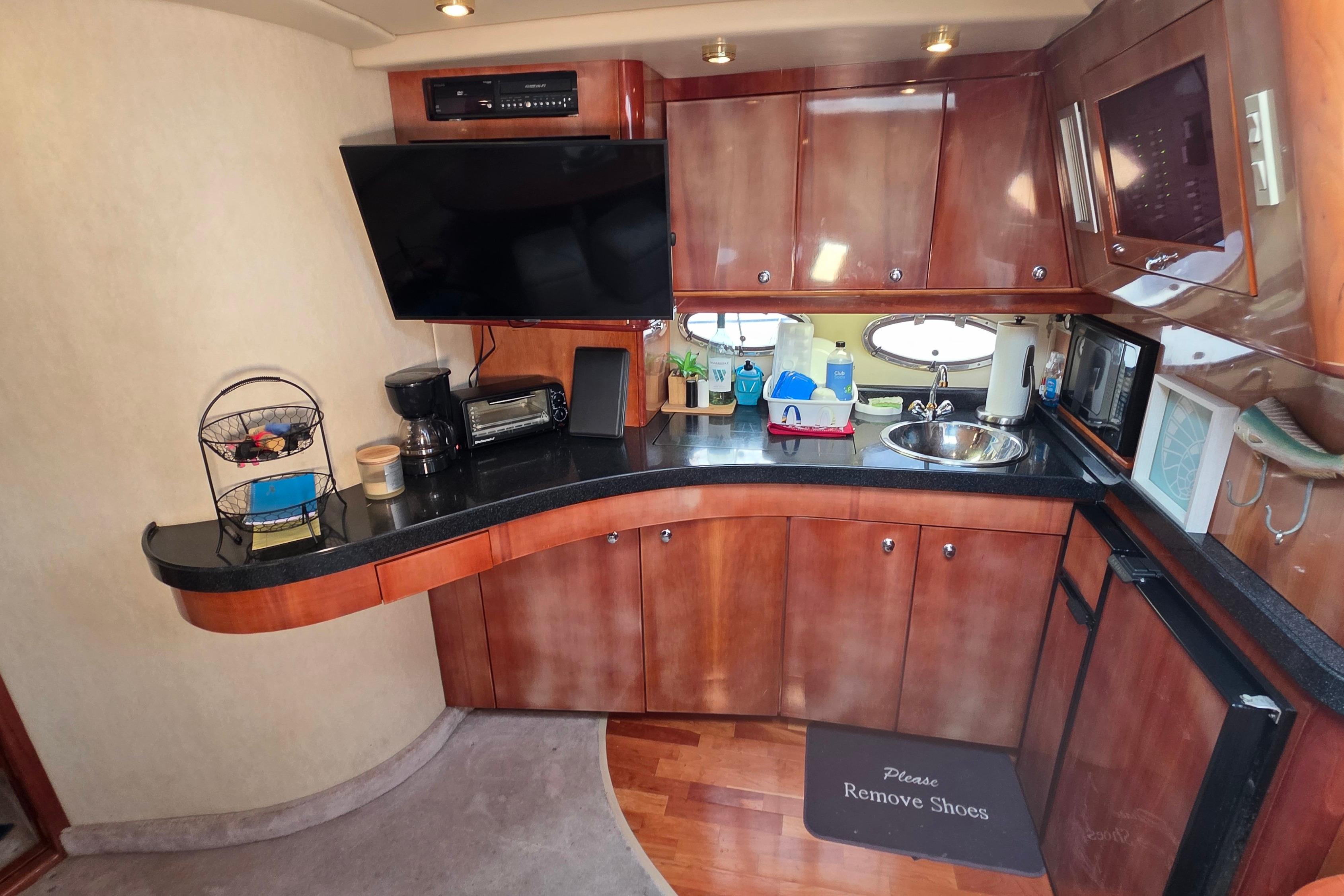 Interior of 2002 Regal Commodore 4260 yacht with kitchenette, TV, and wooden cabinetry.
