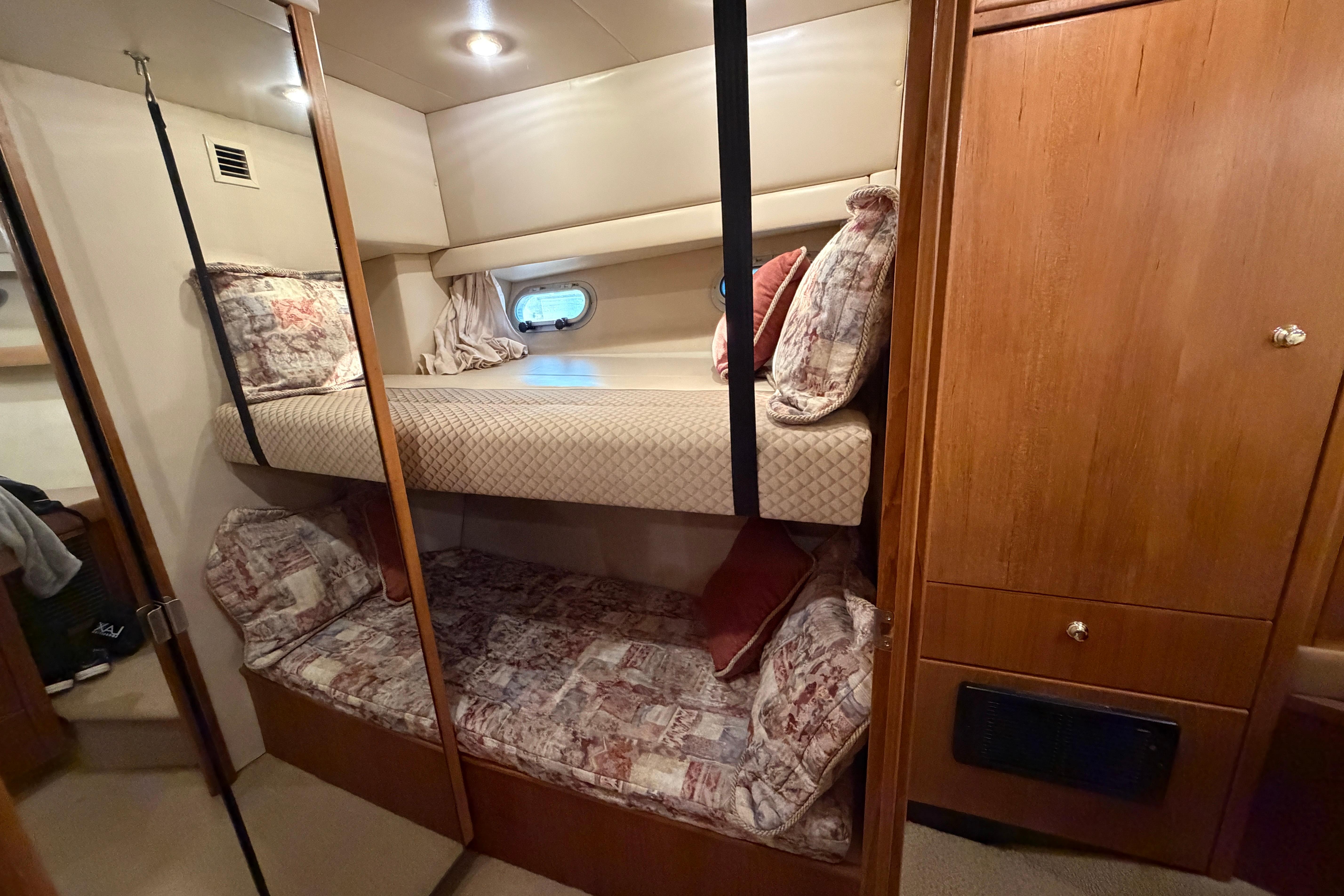 Interior of 1999 Bayliner 4788 Pilot House Motoryacht with cozy bunk beds and wooden cabinetry.