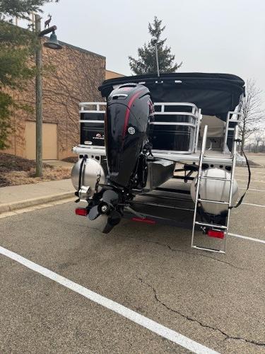 2025 Sun Tracker SportFish 22 DLX pontoon boat with outboard motor in parking lot.