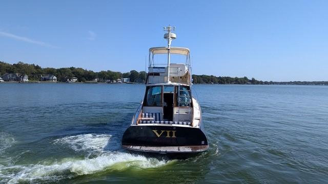 2007 Hinckley Talaria 44 Flybridge cruising on a calm lake under a clear blue sky.