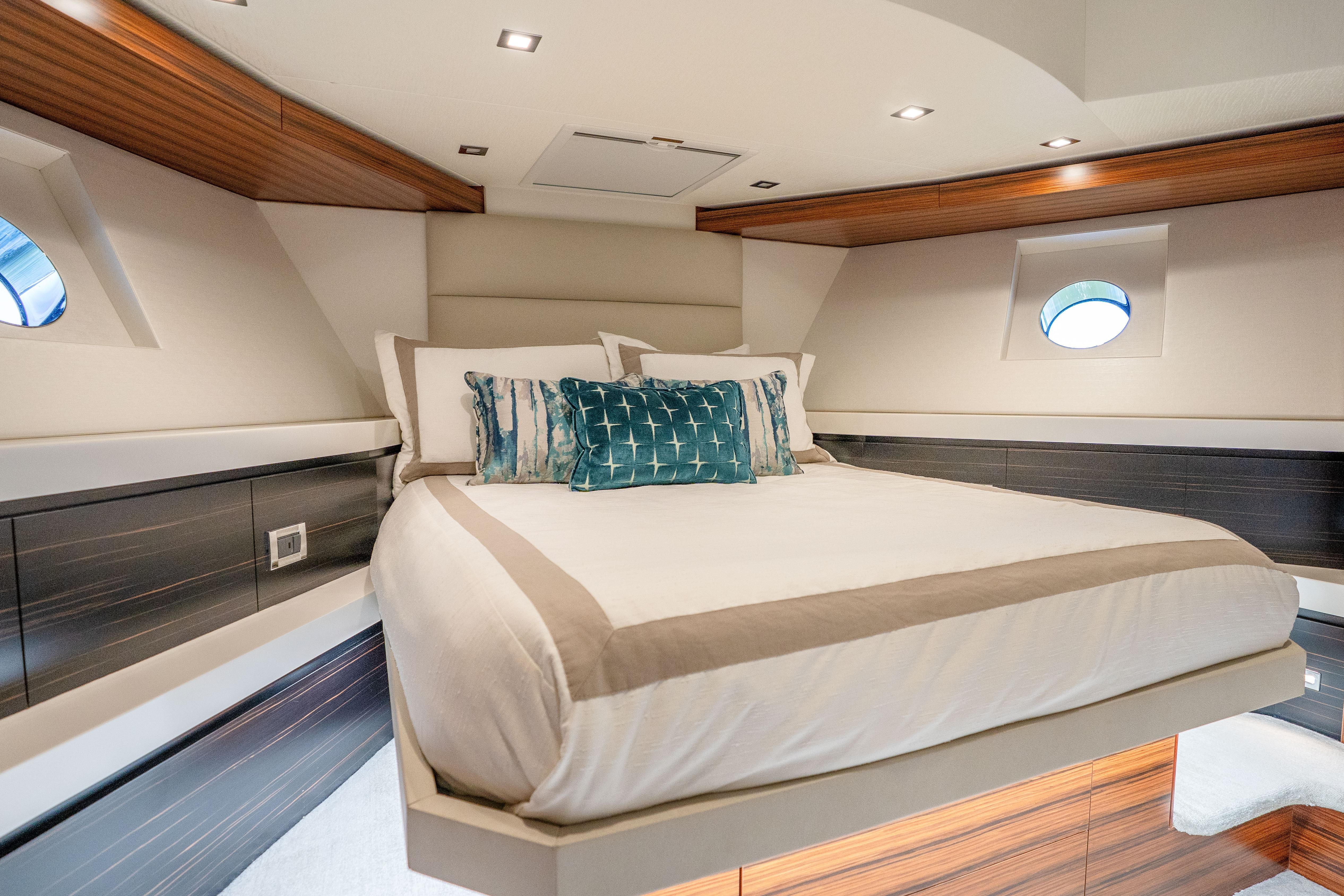 Luxurious bedroom interior of 2021 Hatteras M75 Panacera yacht with elegant bedding and wood accents.