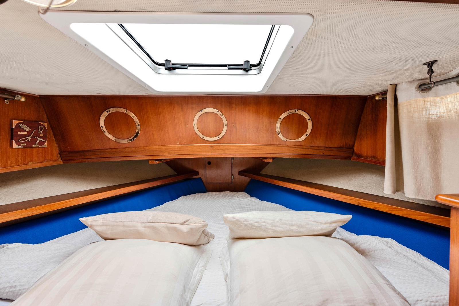 Cozy cabin interior of 1979 Eurobanker 41 Trawler with wooden accents and portholes.