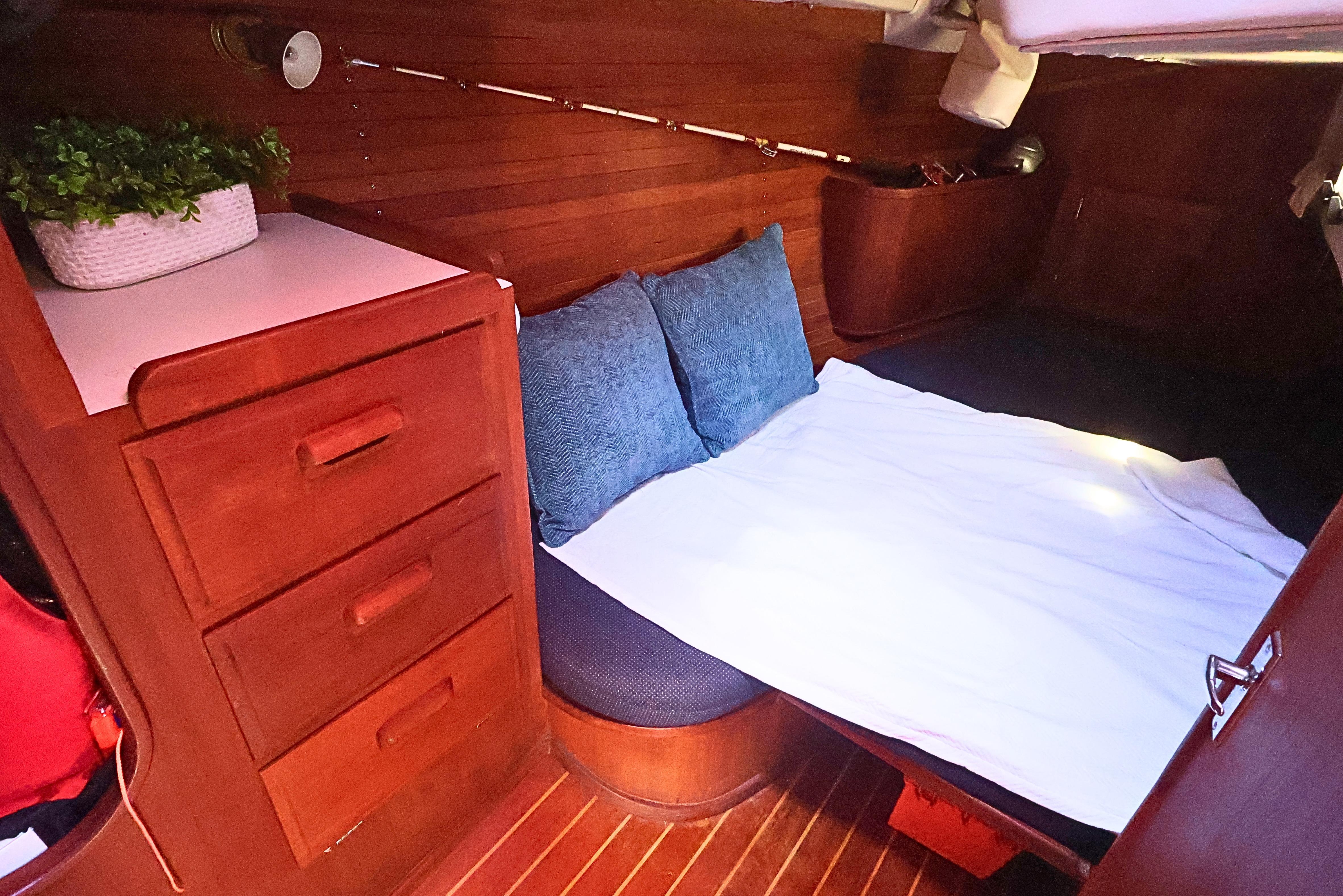 Cozy cabin interior of 1989 J Boat J 40 with wooden drawers and bedding.