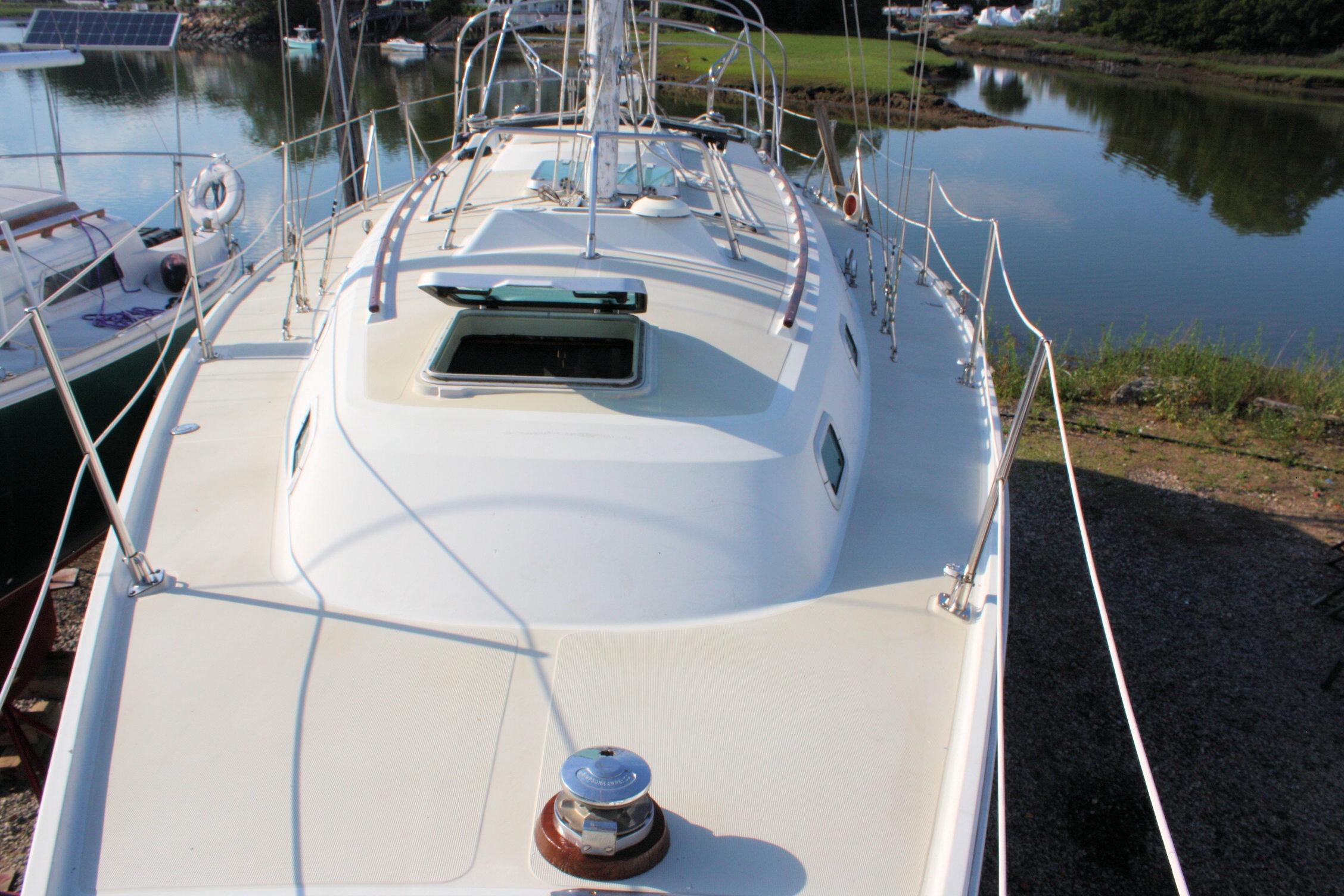 1987 Ericson 38-200 sailboat deck view, docked near calm water and greenery.