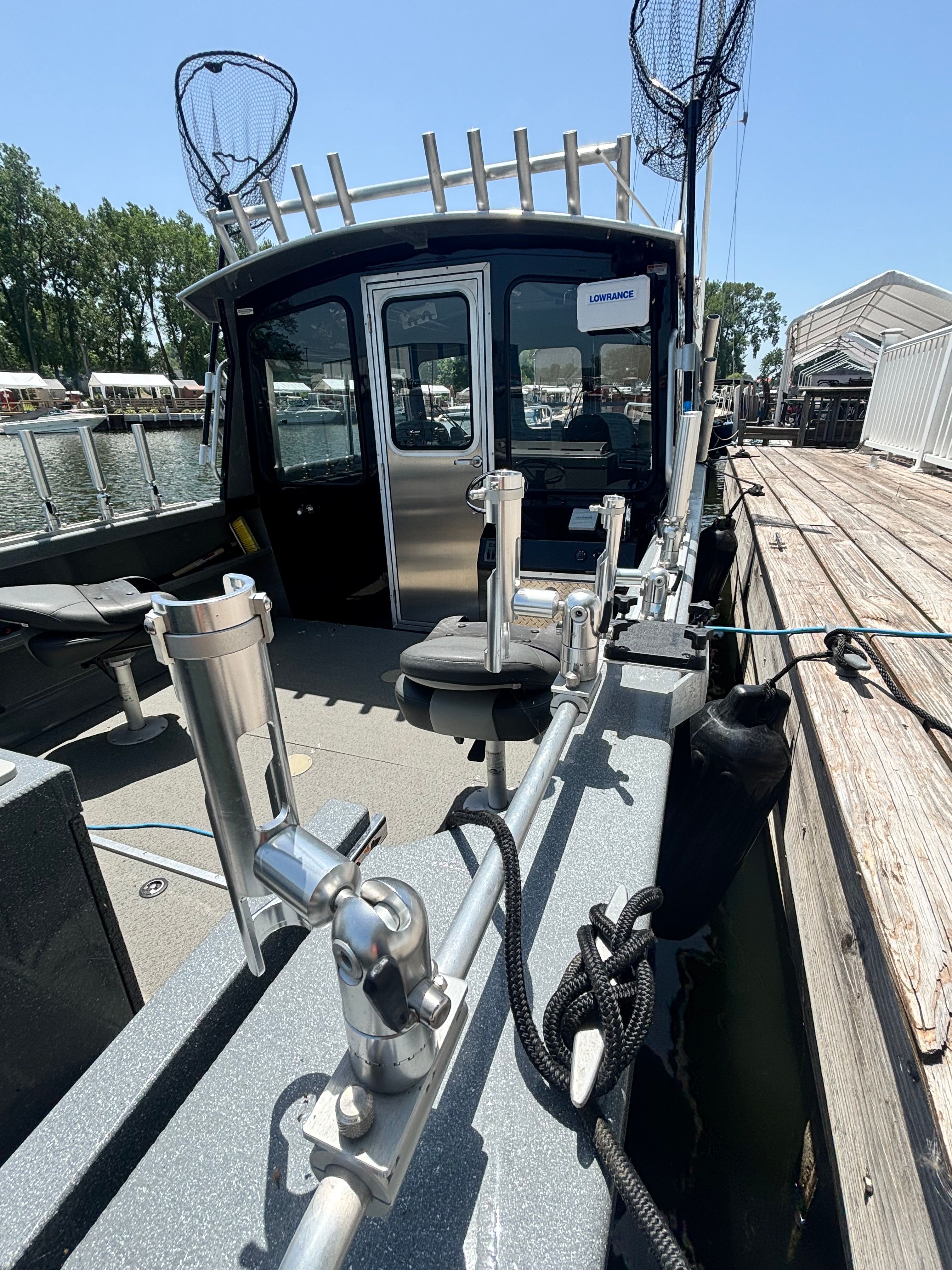A sturdy fishing boat with rod holders and nets, docked at a pier.