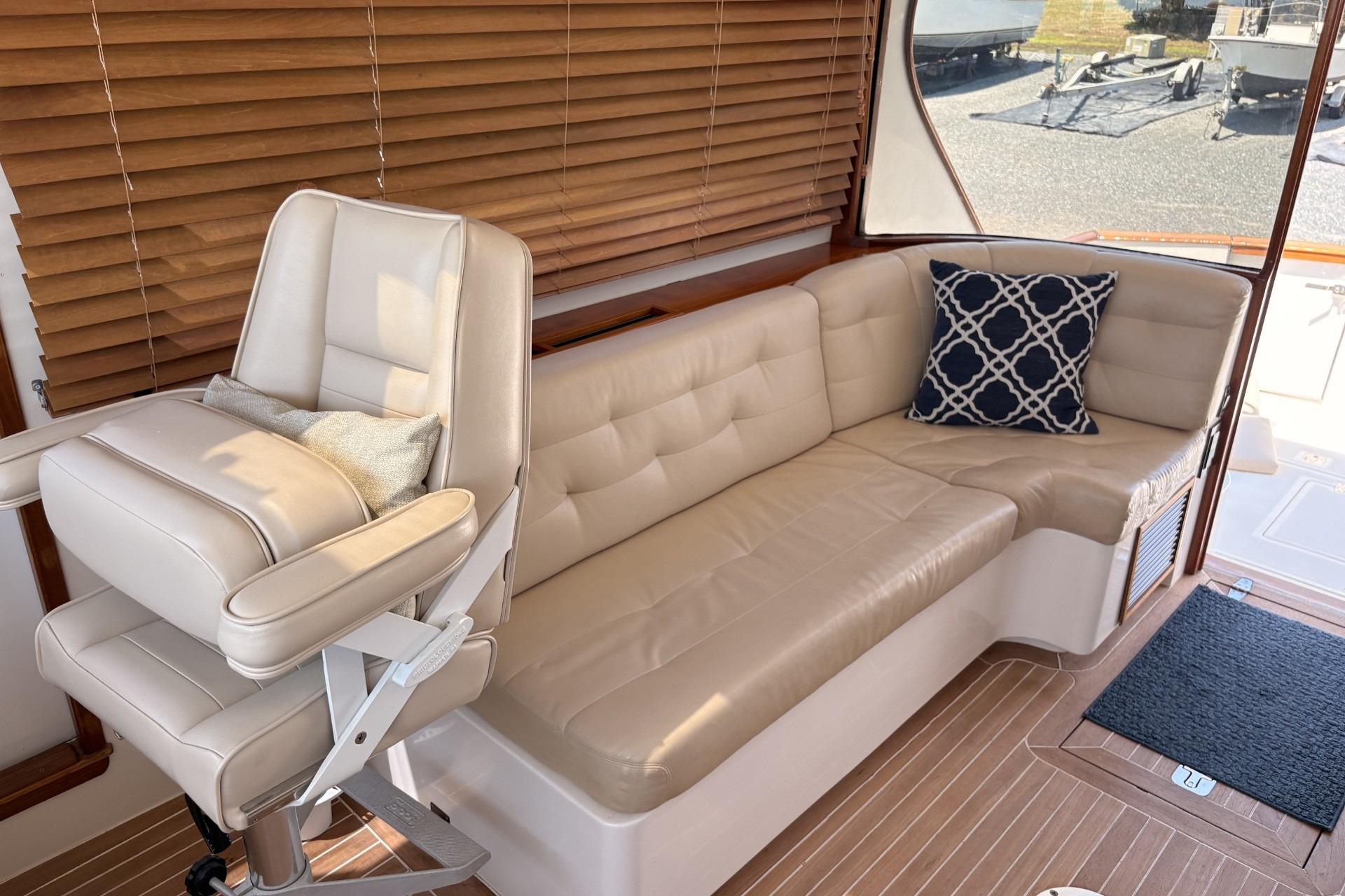 Luxurious boat interior with beige seating, patterned cushion, and wooden blinds.