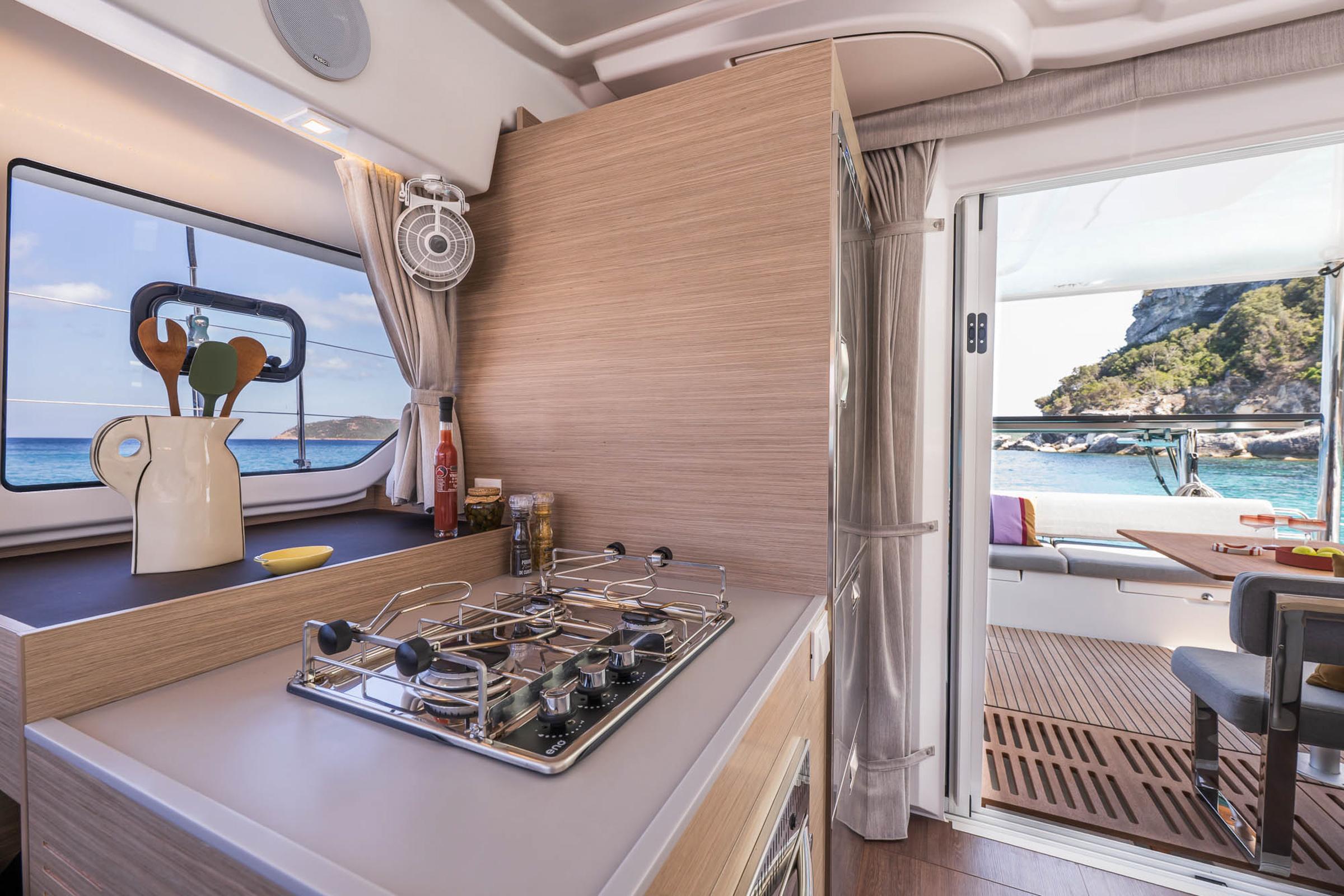 Modern kitchen interior of 2025 Lagoon 38 yacht with ocean view and outdoor seating.