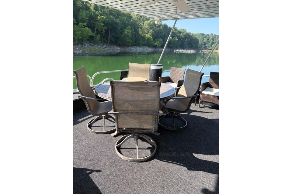 Outdoor seating on 1997 Stardust Houseboat 18x83, overlooking serene lake and lush greenery.