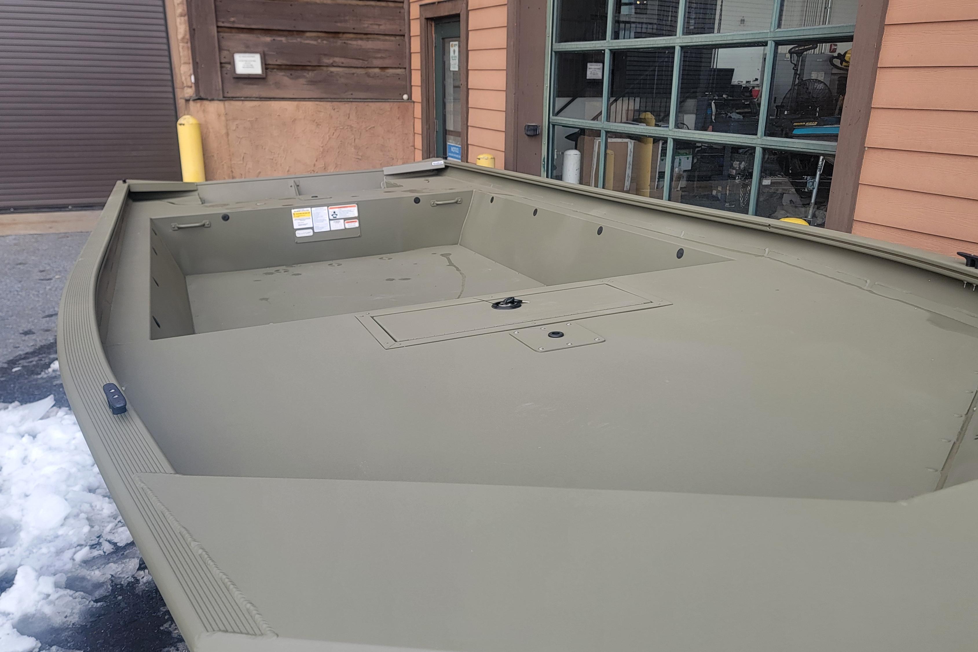 2026 Tracker Grizzly 1860 Utility boat, olive green, parked outside a building.