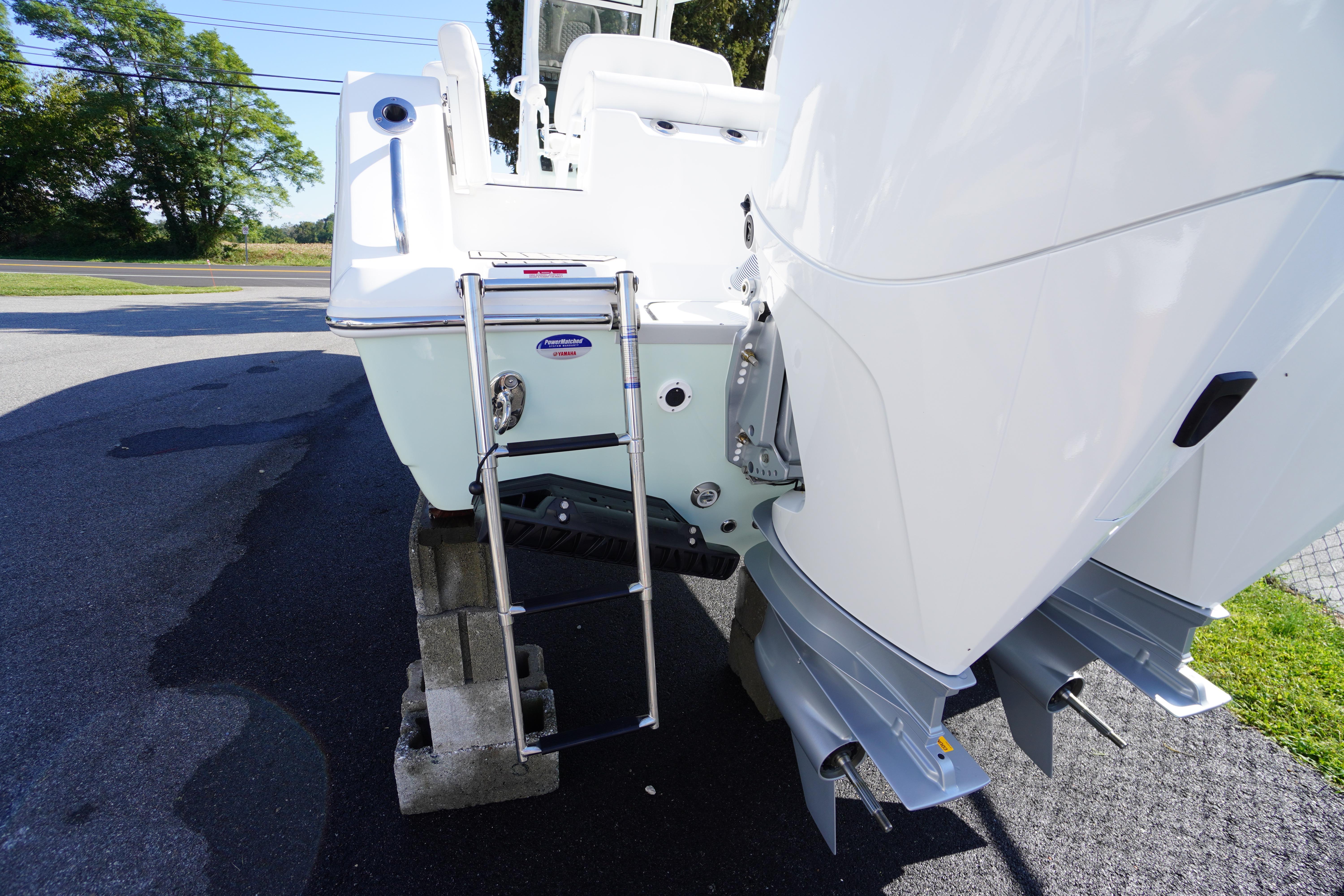 2026 Tidewater 272 LXF boat with ladder and dual outboard motors on display.