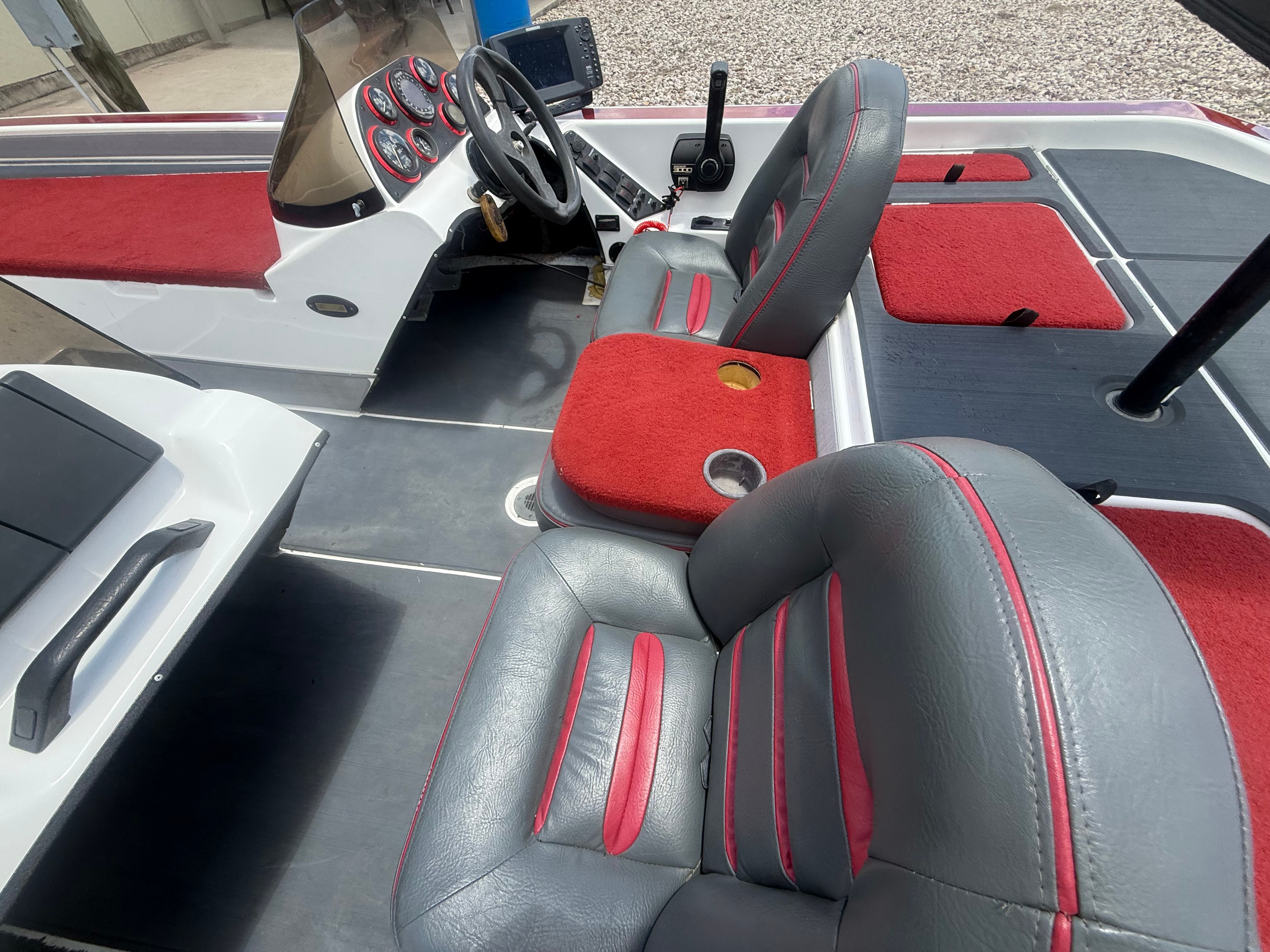 The image shows the cockpit of a 1999 Champion 202 boat with gray and red seats.