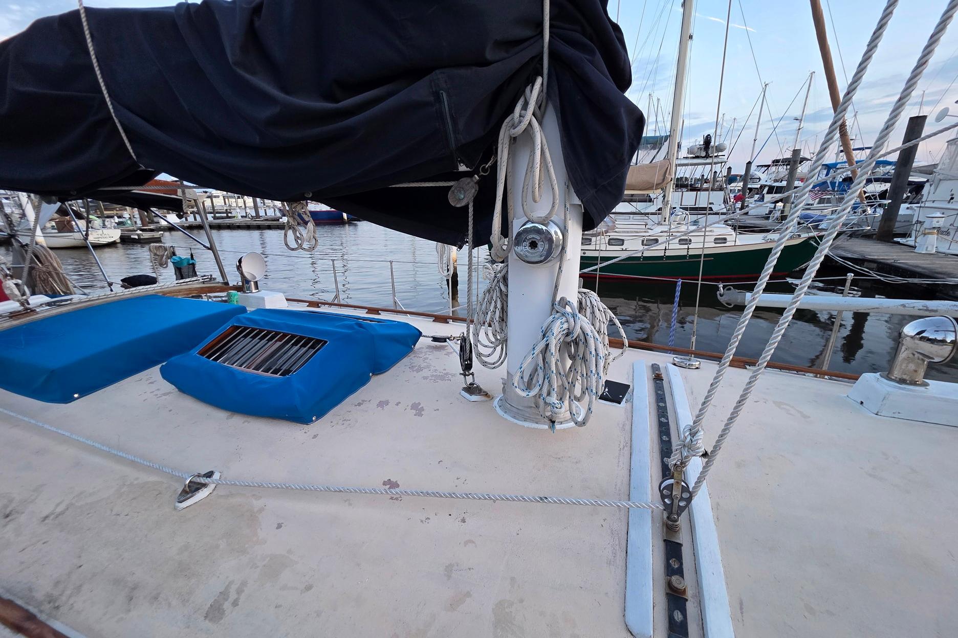 Deck of 1982 Tayana 37 sailboat with ropes and covered equipment at marina.