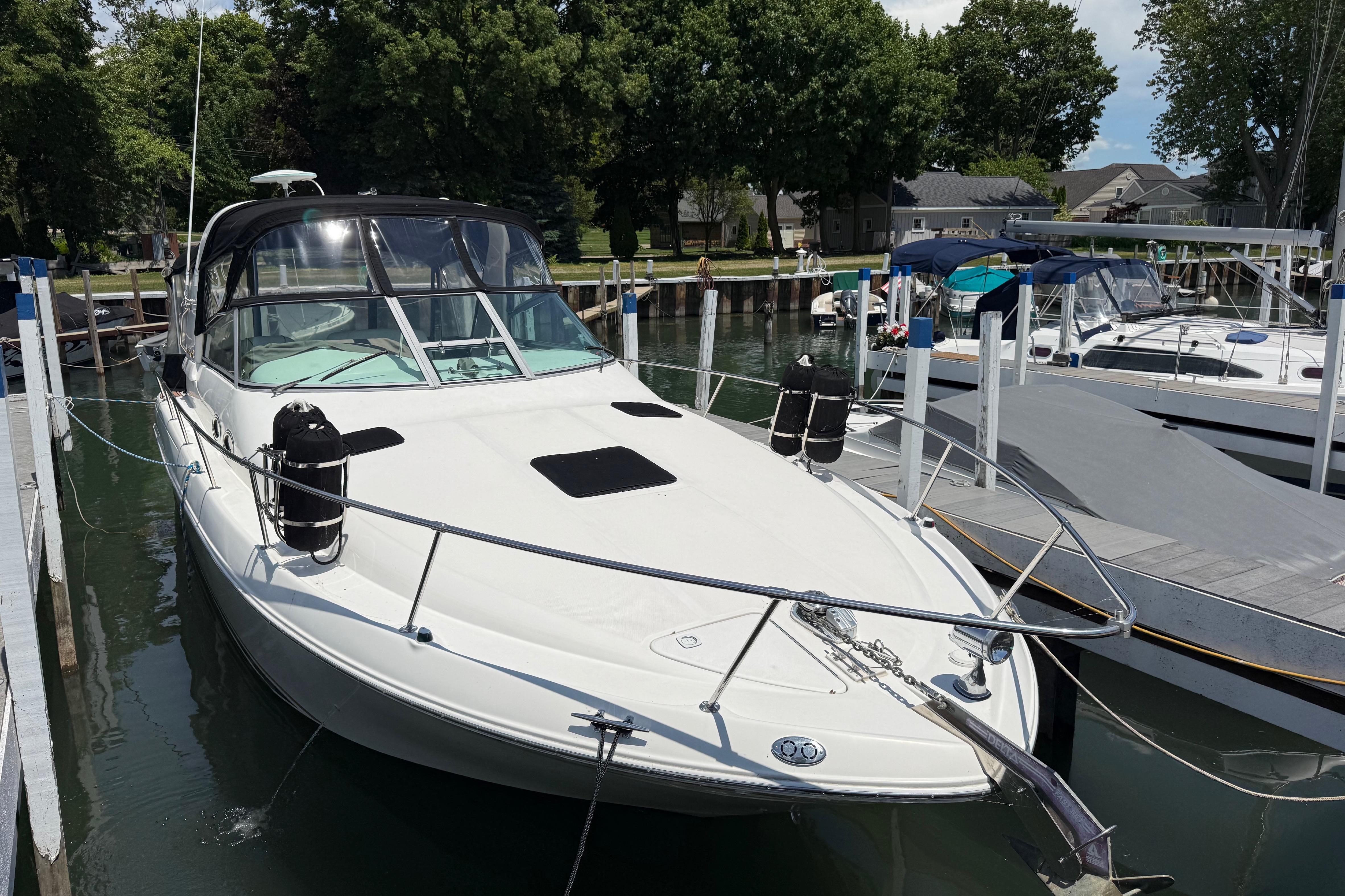 1999 Sea Ray Sundancer 310 docked at marina, surrounded by trees and other boats.