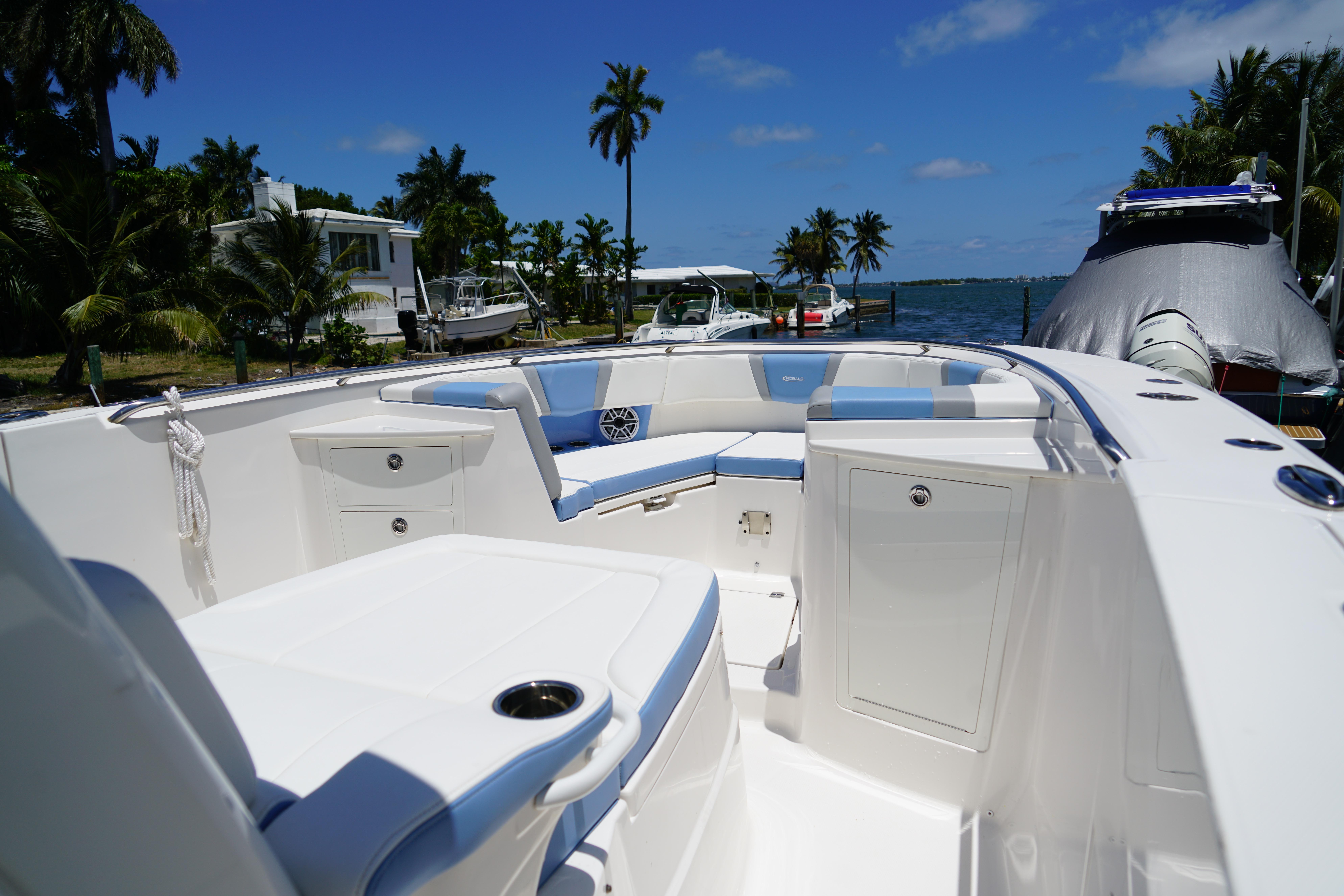 2024 Robalo R360 Center Console boat with spacious seating, docked near palm trees and water.