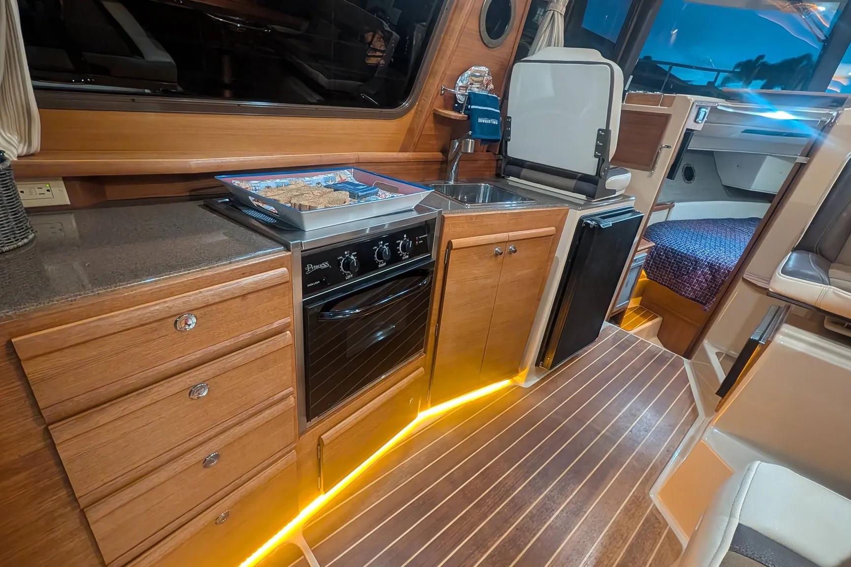 Interior of 2015 Ranger Tugs R-29 S, featuring a compact kitchen with wood cabinetry.