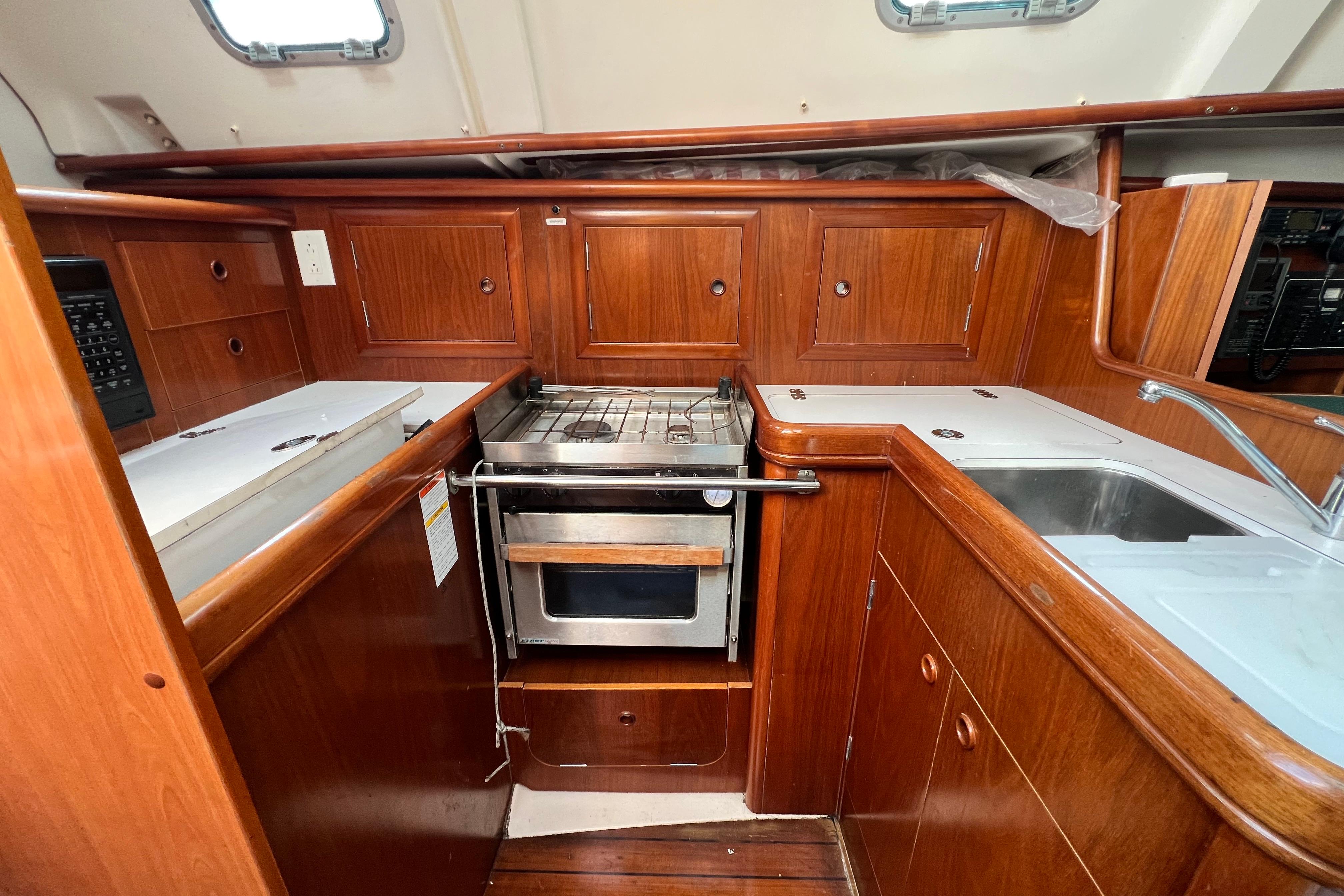 2001 Beneteau 331 yacht kitchen with wooden cabinetry, stove, and sink.