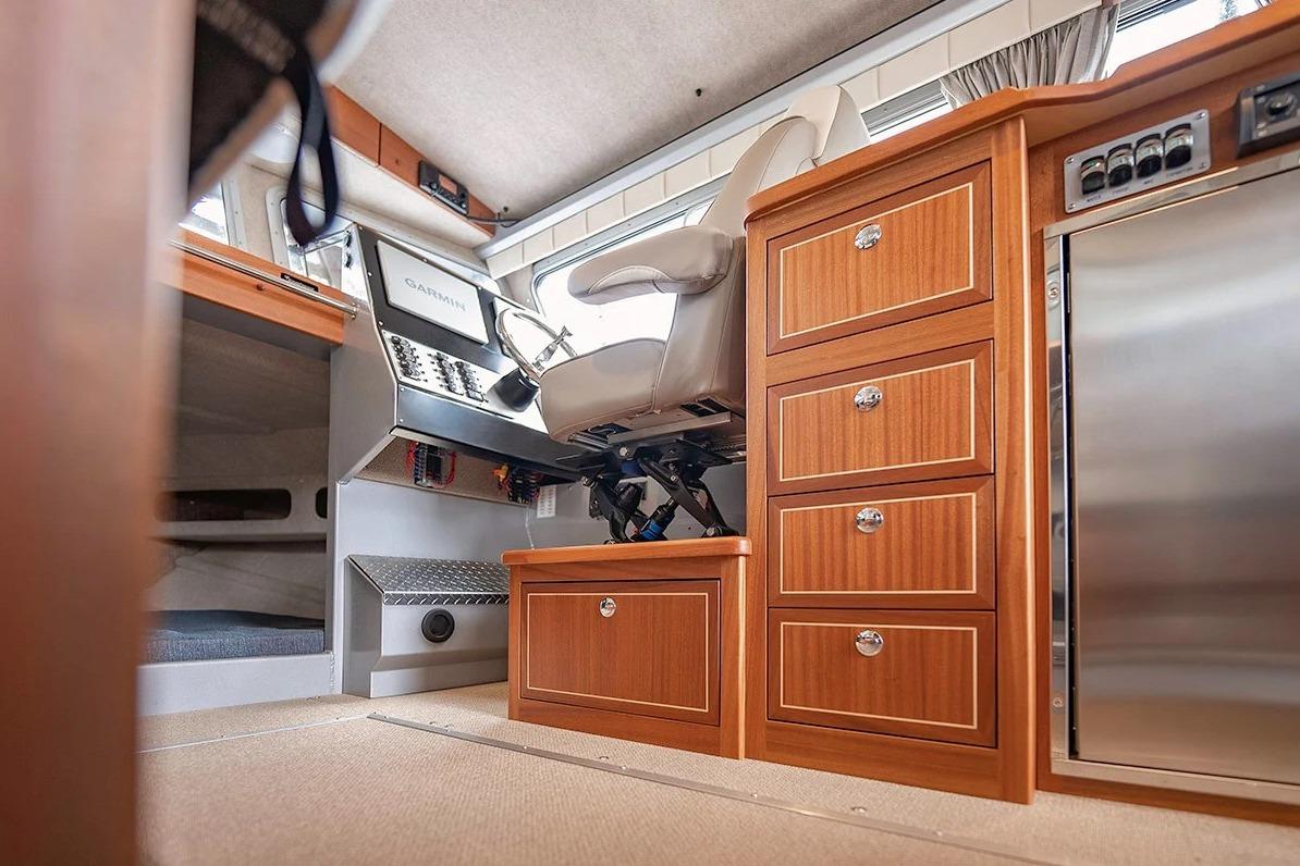 Interior of 2026 KingFisher 3225 GFX Offshore boat with helm, wooden cabinetry, and modern controls.