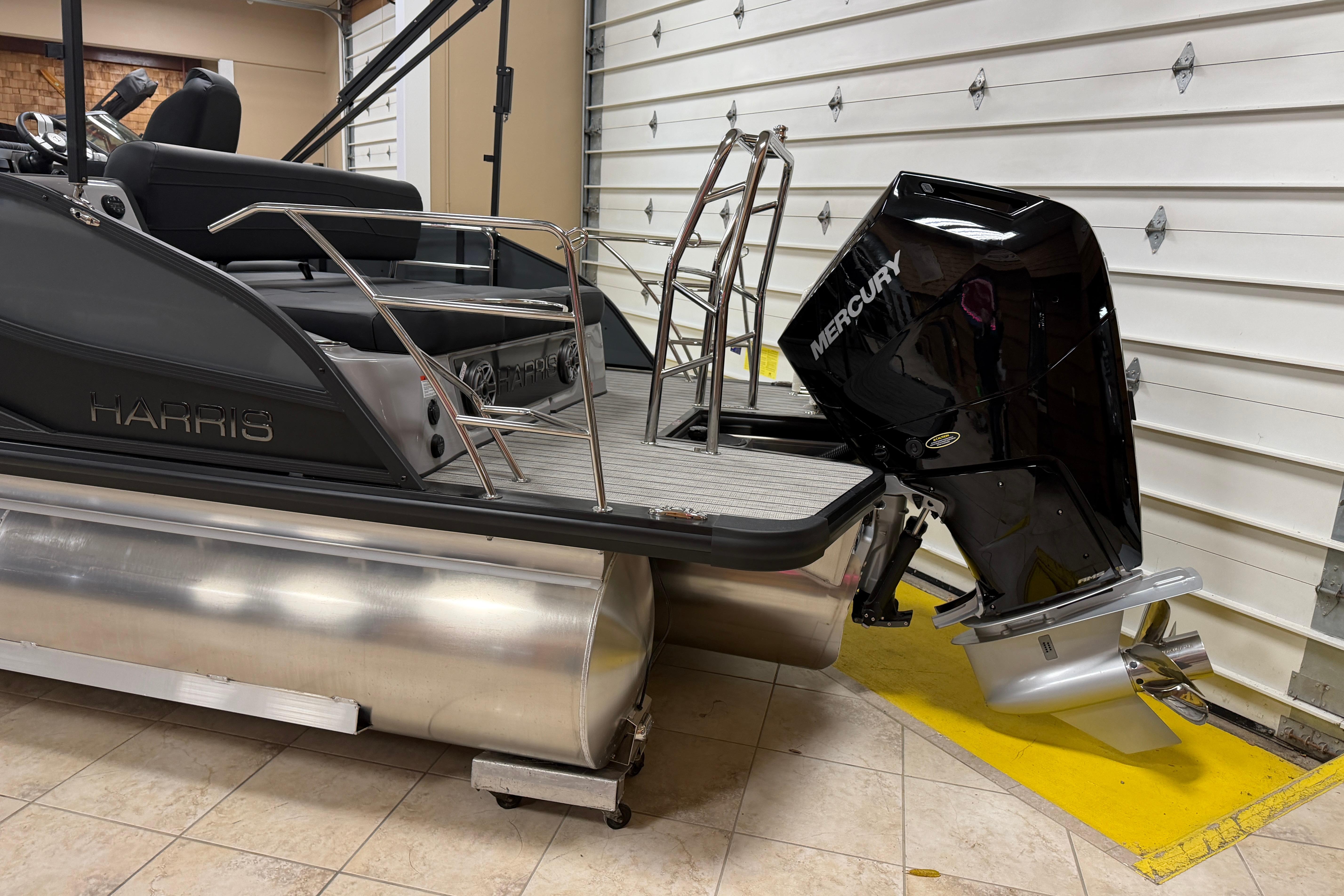 2026 Harris Grand Mariner 250 pontoon boat with Mercury outboard motor in garage.