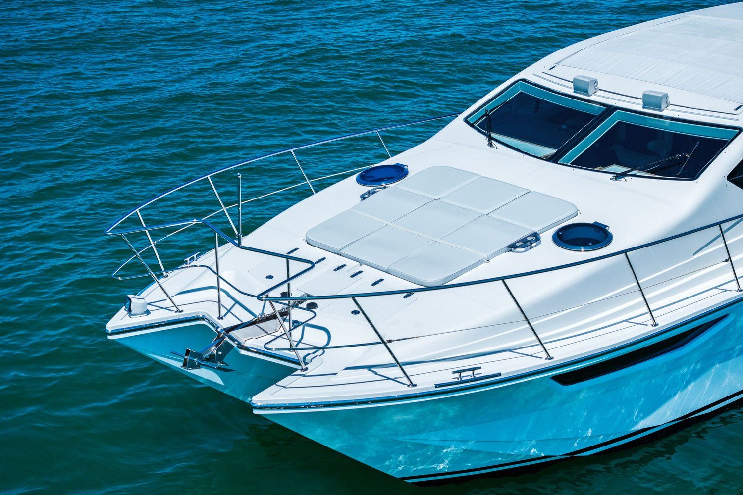 A white catamaran with a blue underside on calm water.