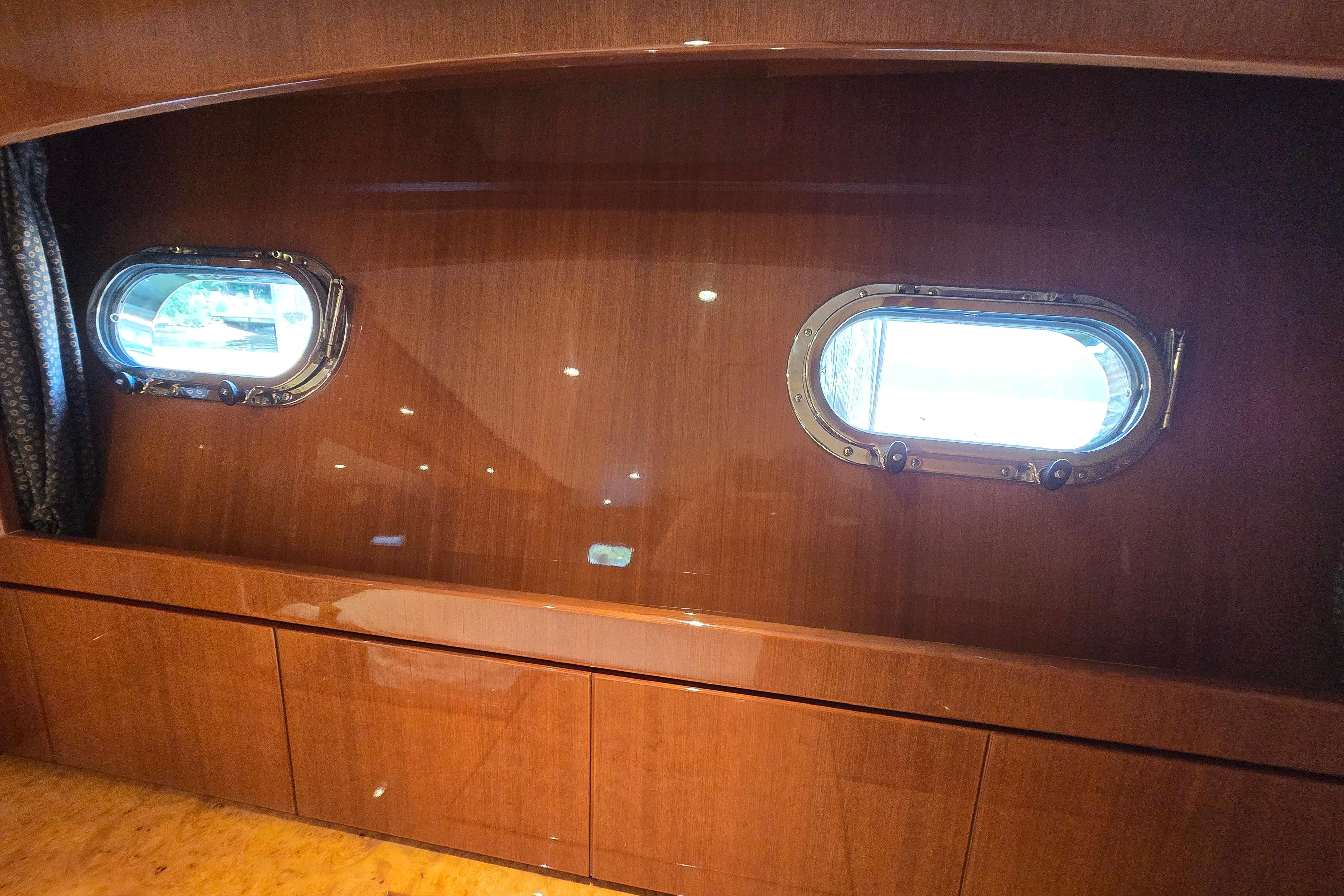 Luxurious wooden interior of 2004 Grand Harbour 58 yacht with two porthole windows.