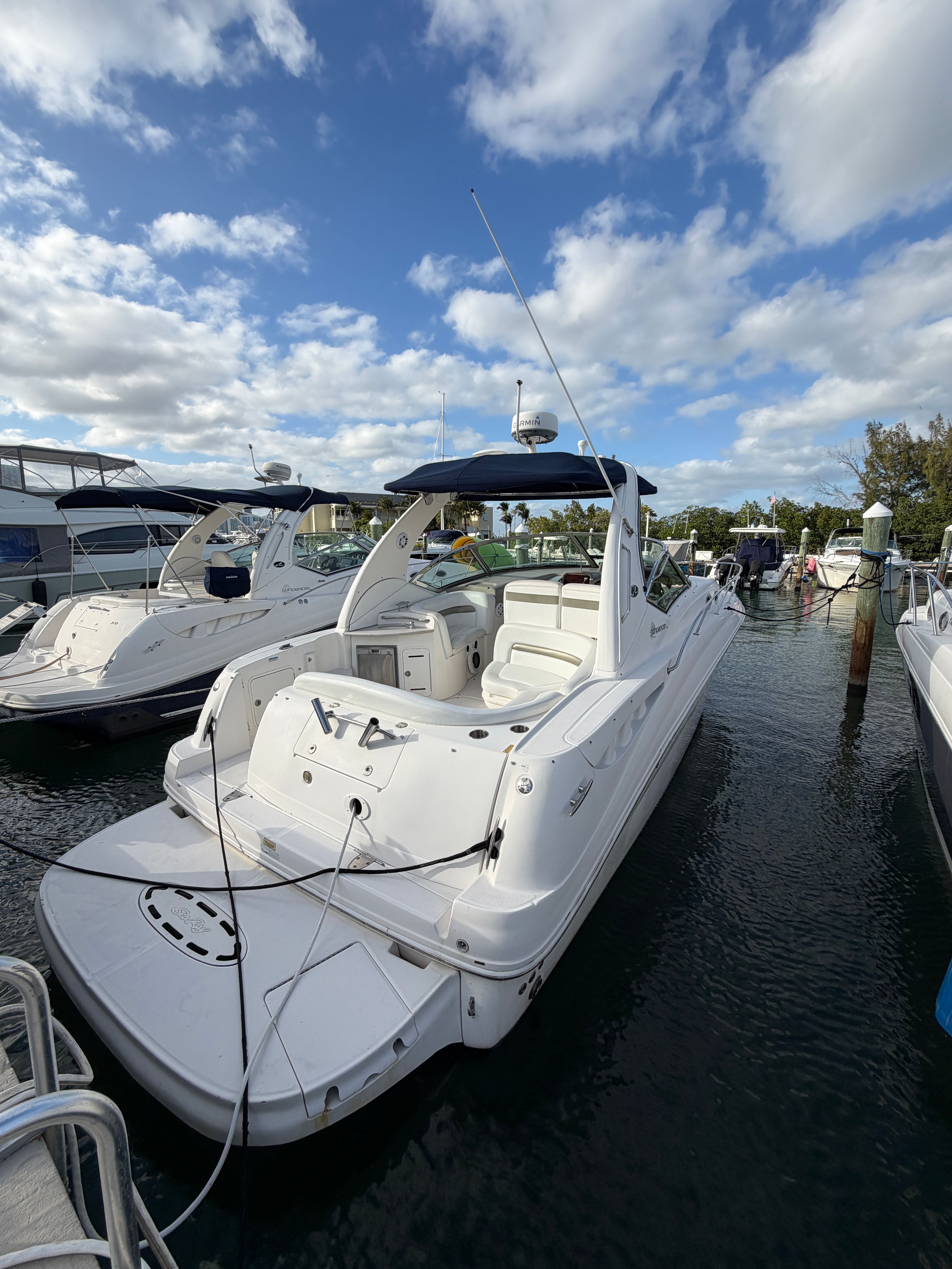 A 2006 Sea Ray Sundancer 320 is docked in the water. The sky is cloudy.