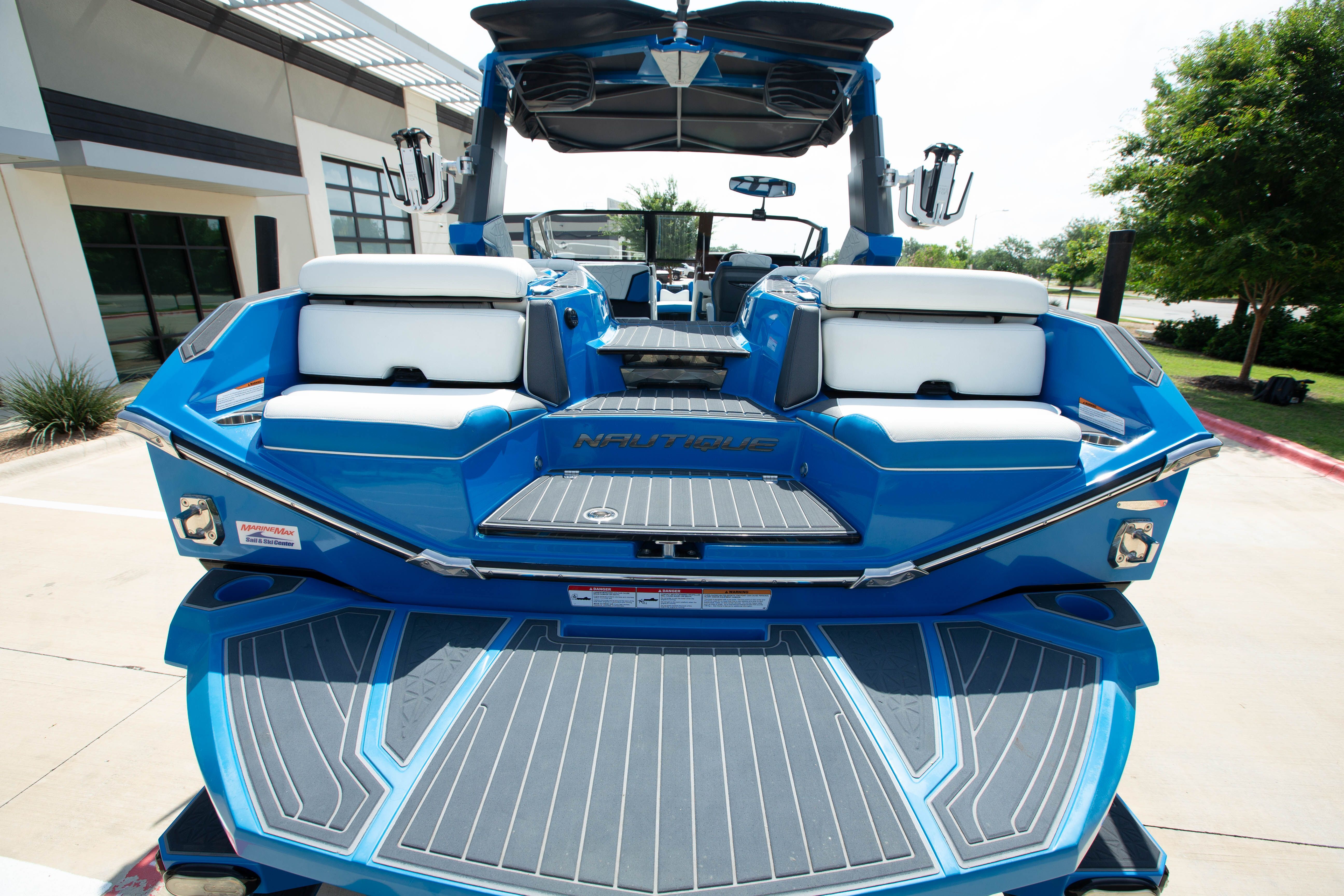 A blue boat with white seats, parked on a concrete lot.