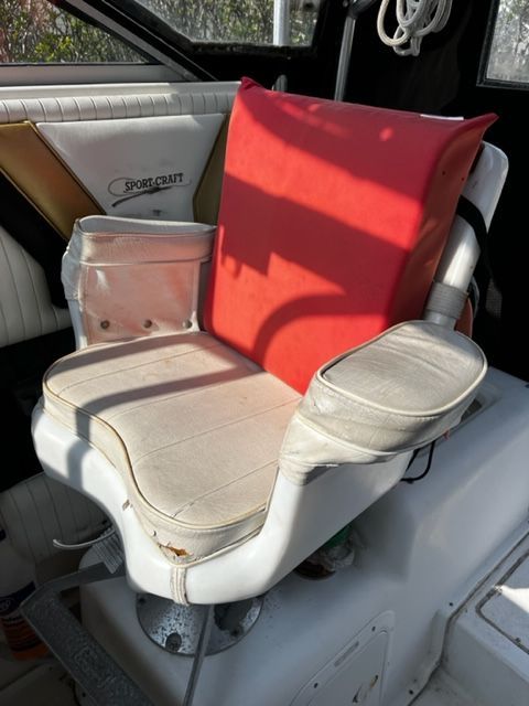 A white boat seat with red cushions, surrounded by black and white interior.