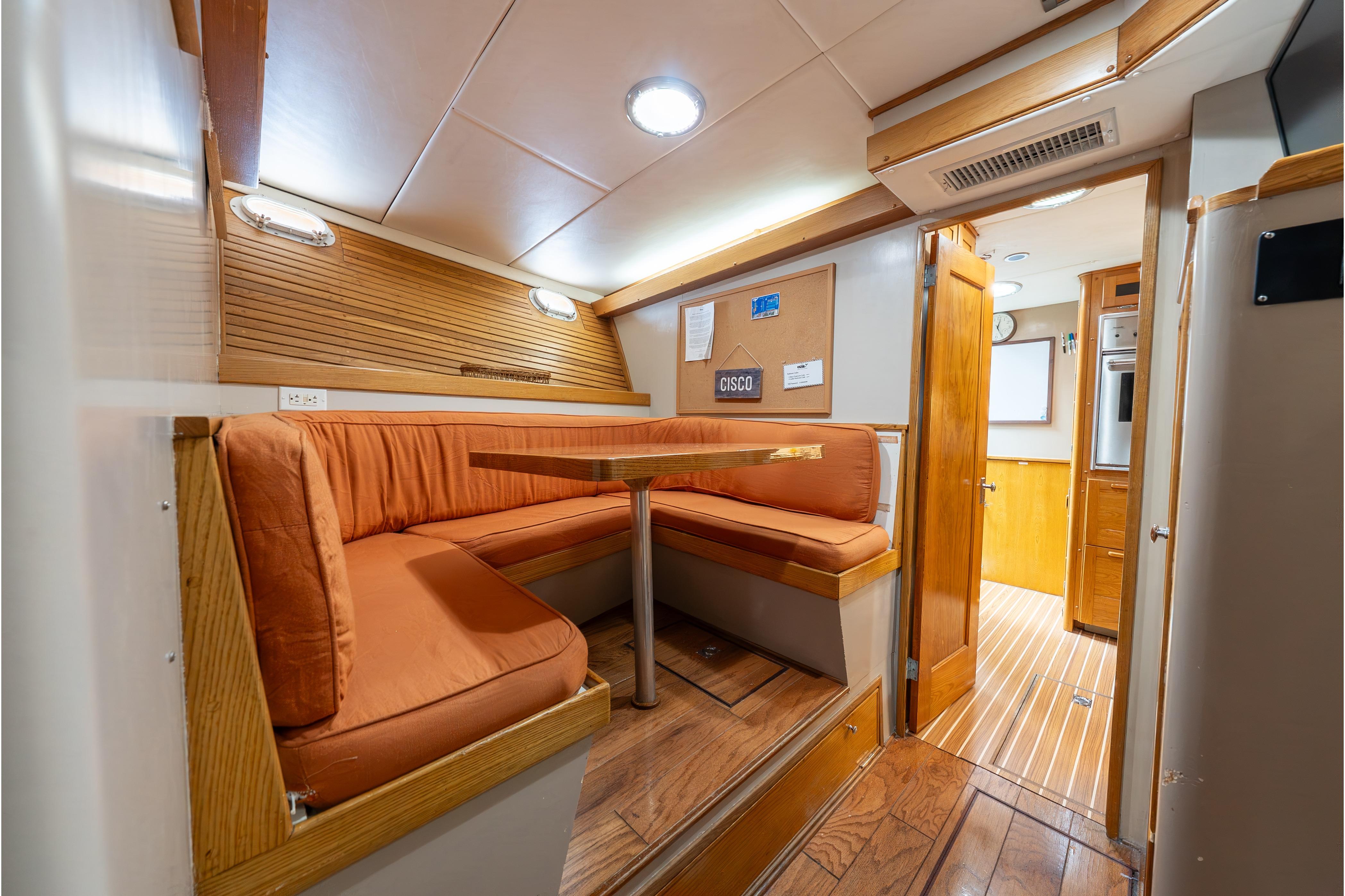Interior of a 1963 Trumpy Classic yacht with cozy dining area and wooden accents.