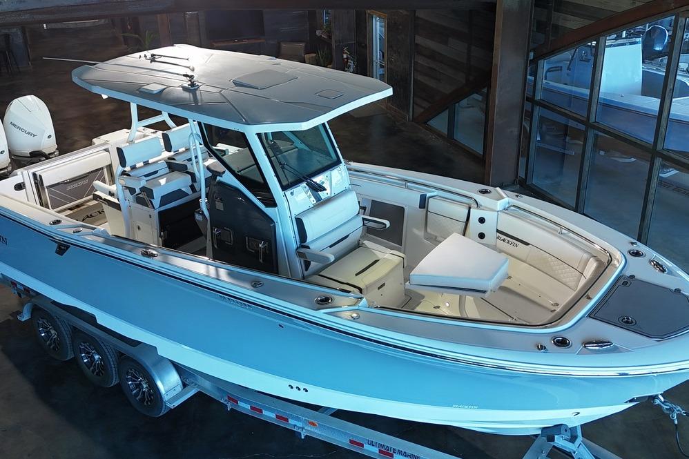 2023 Blackfin 302 CC boat on trailer in showroom, showcasing sleek design and spacious interior.
