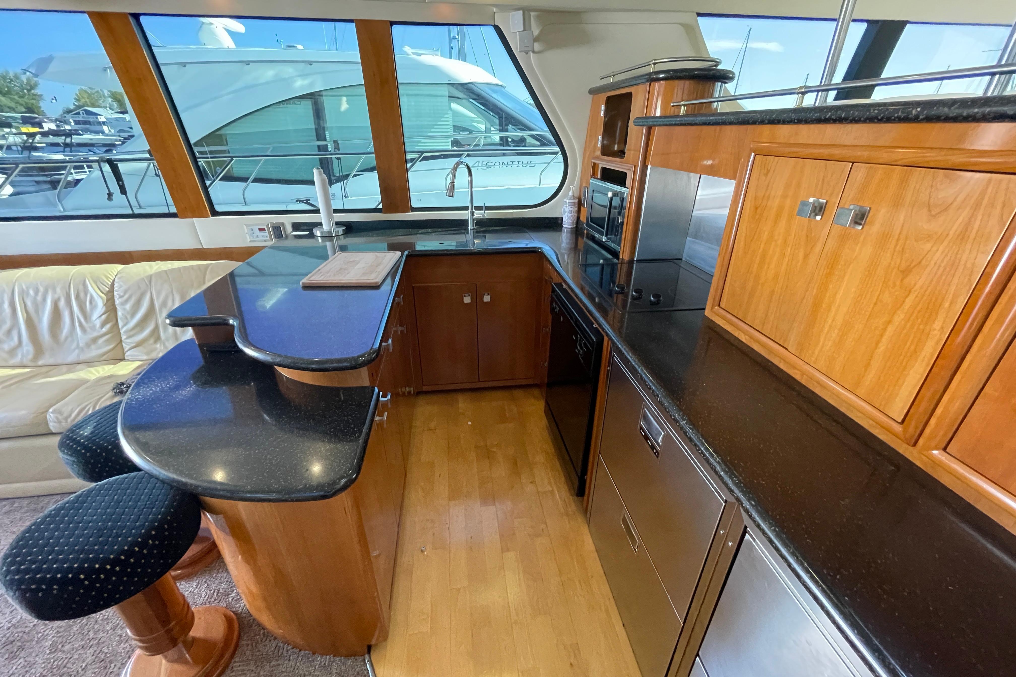 Luxurious kitchen interior of 2002 Carver 570 Voyager Pilothouse yacht with wood and black countertops.