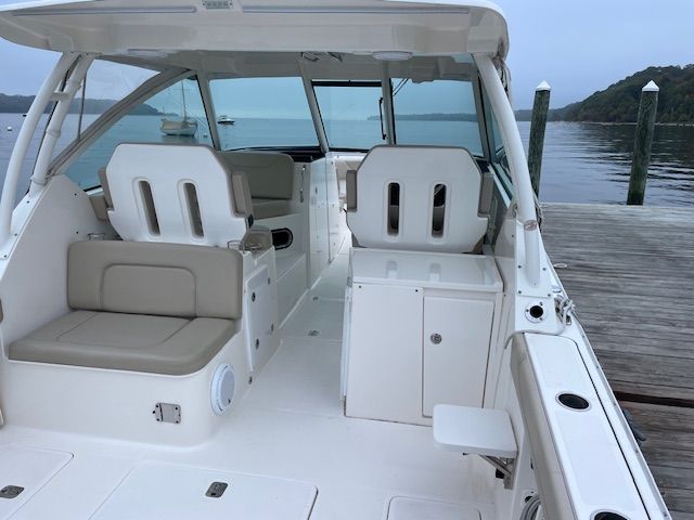 The boat features an open cabin with two seats and a sofa. It is docked.