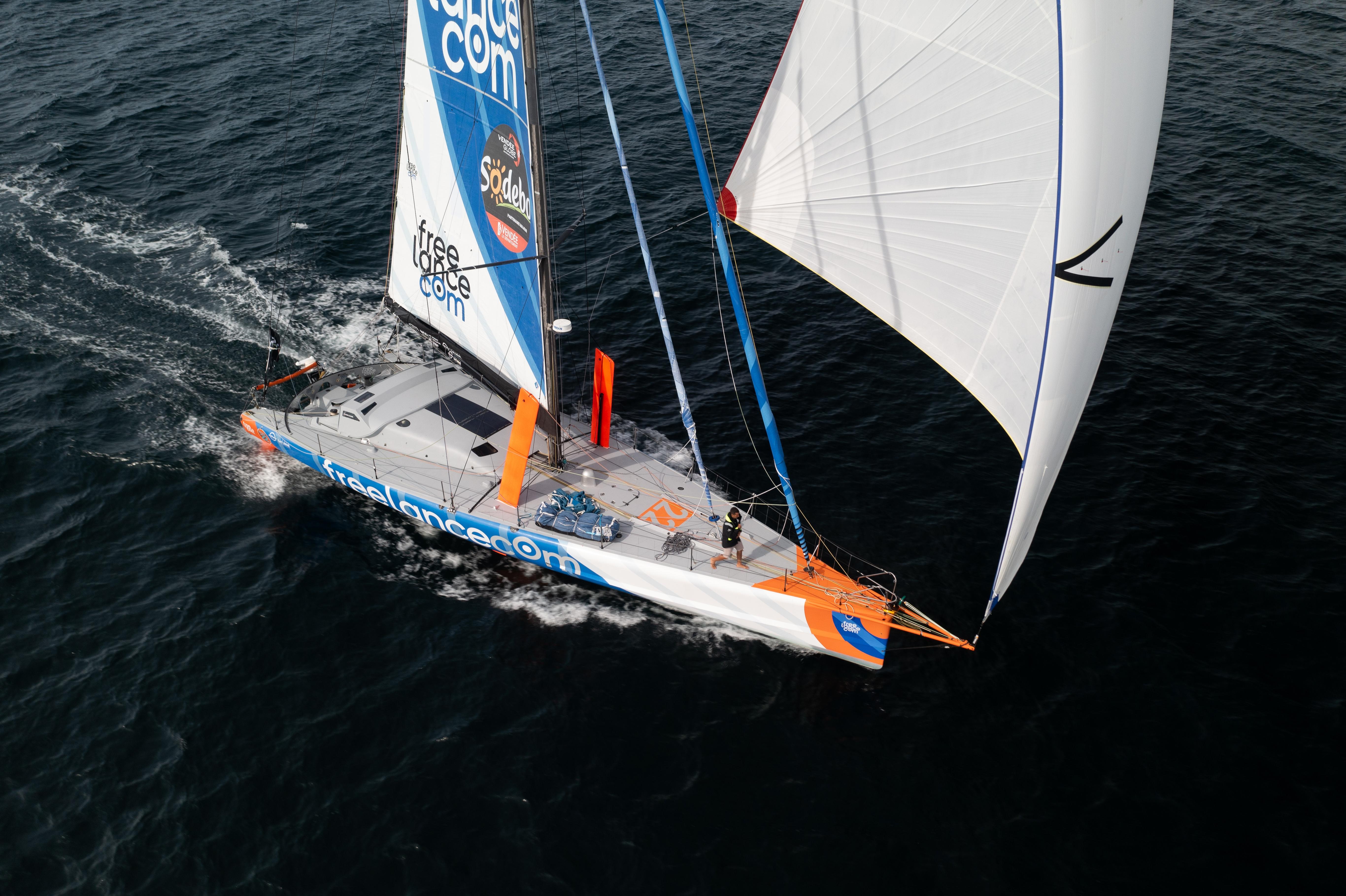 Sailing yacht IMOCA 2007 gliding on open water with full sails.