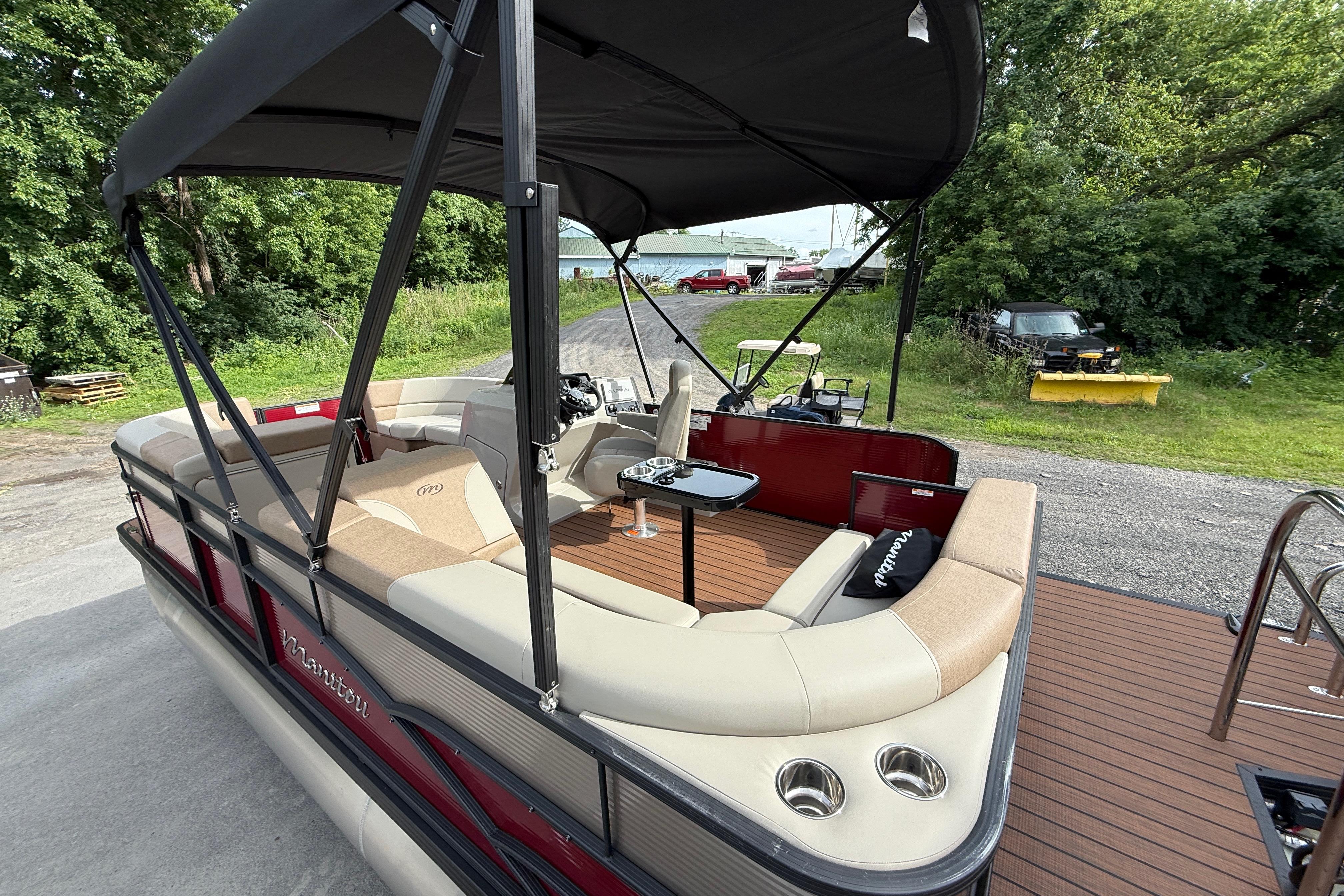 2027 Manitou 21 Aurora LE pontoon boat with spacious seating and canopy, docked outdoors.