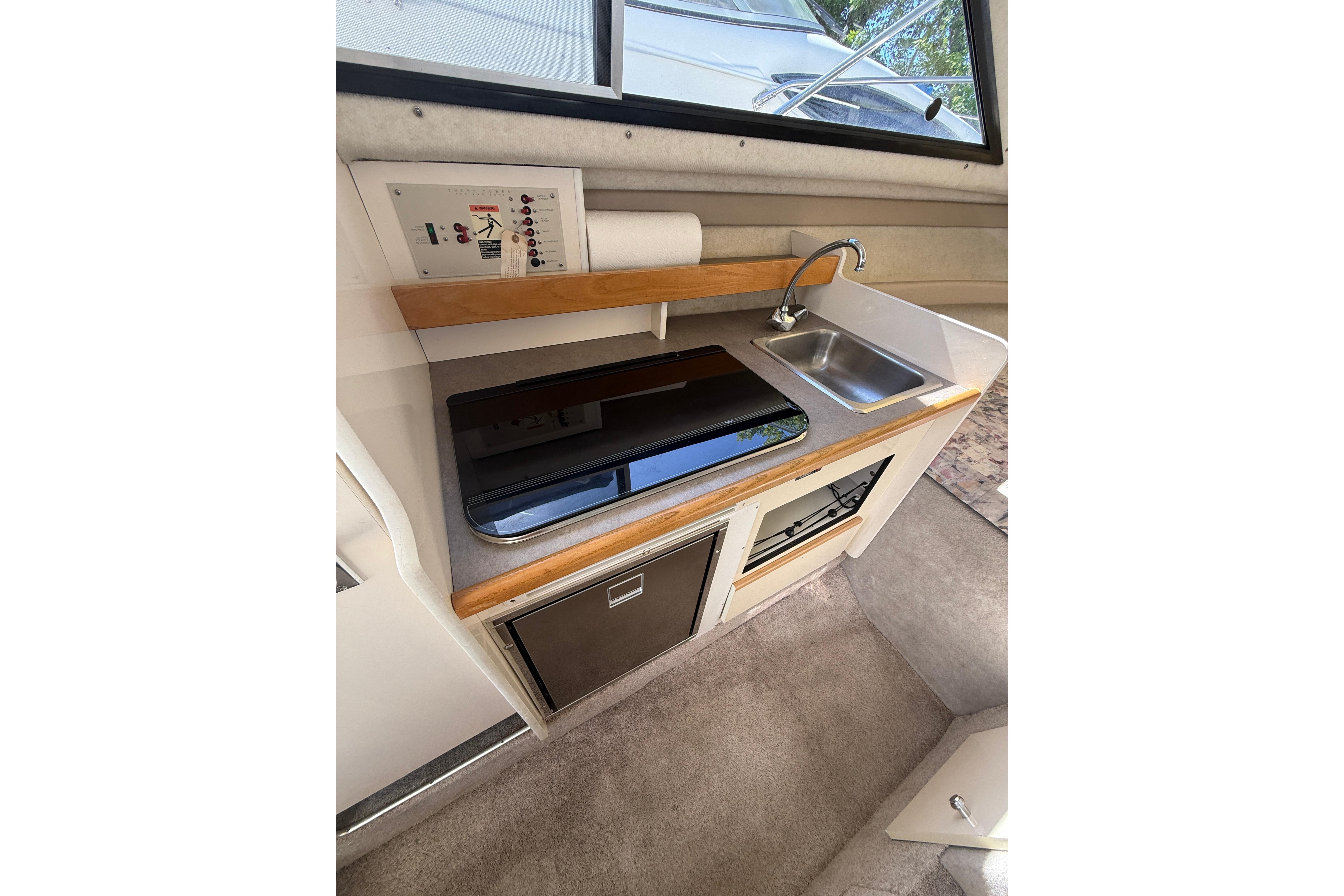 Compact kitchen area in a 1997 Bayliner 2452 Ciera Express boat, featuring a sink and stove.